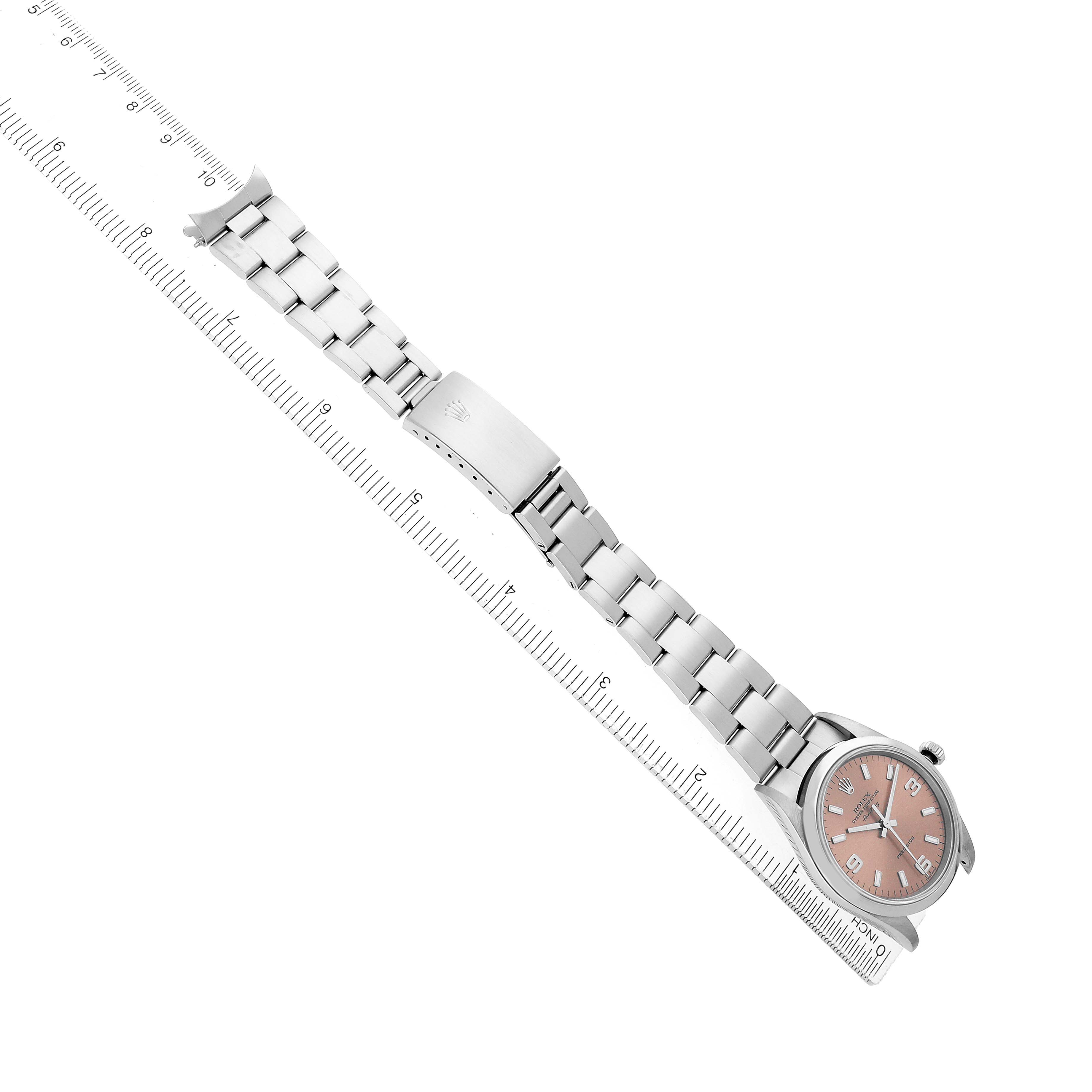 The Rolex Air-King 14000 Men's Stainless Steel Pink Dial watch is shown from an overhead angle, displaying the full bracelet, clasp, and face next to a ruler.