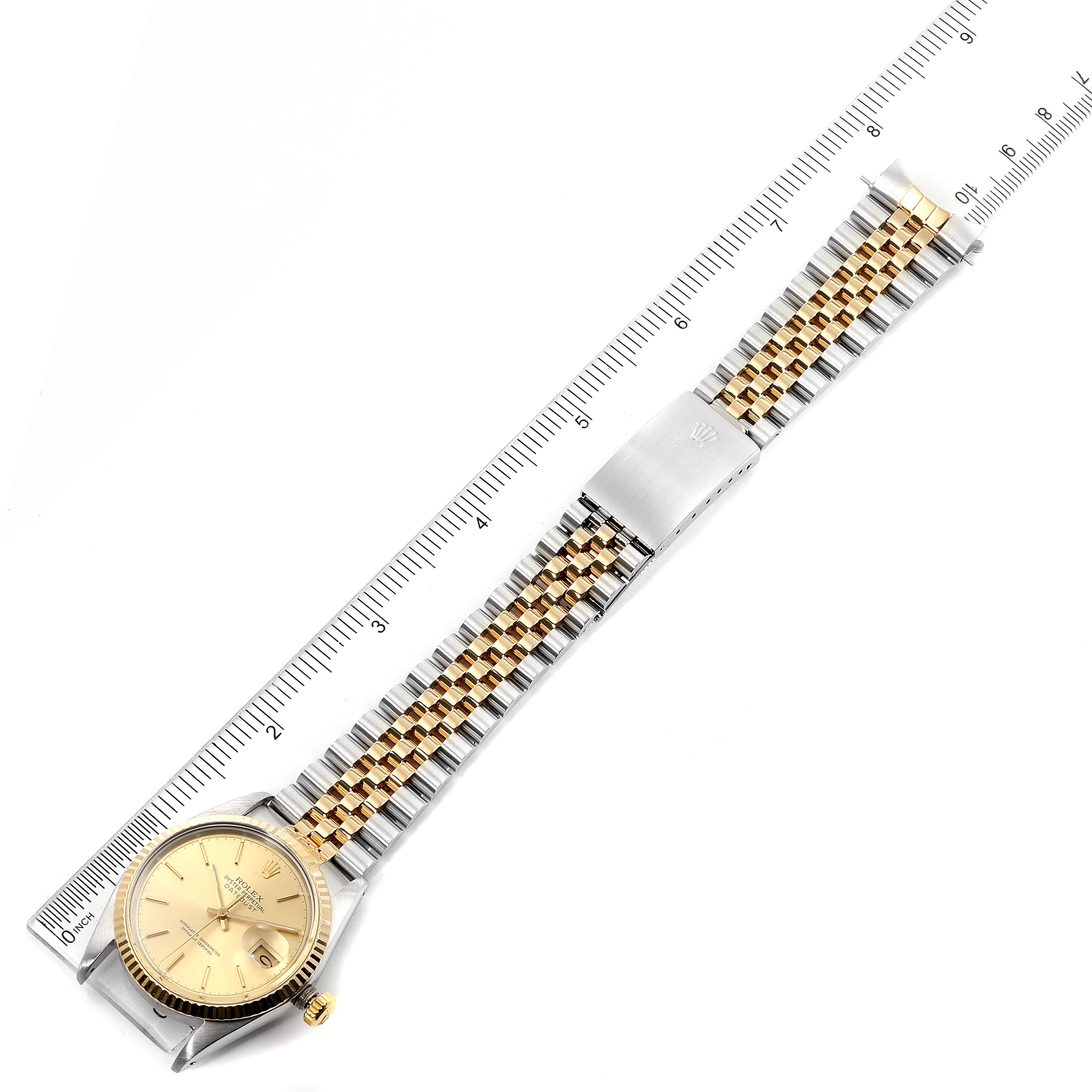 This image shows a Rolex Datejust 16013 Men's Steel and Gold (two tone) Champagne Dial 16013 Men's Steel and Gold (two tone) Champagne Dial watch laid flat, with its gold and stainless steel bracelet extended alongside a ruler for measurement.