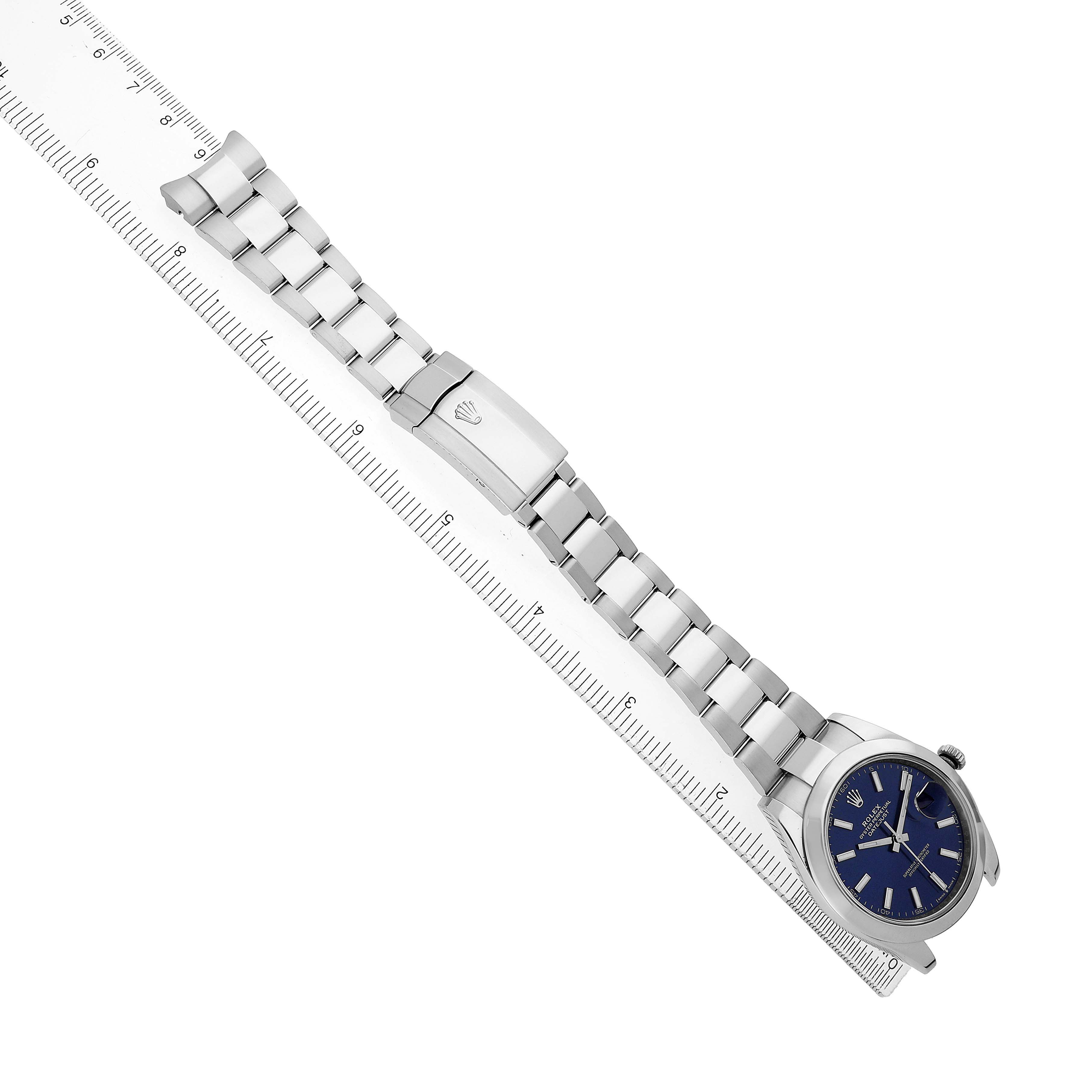 The Rolex Datejust 41 126300 Men's Stainless Steel Blue Dial is shown at an oblique angle, displaying its metal bracelet and clasp fully extended alongside a ruler.