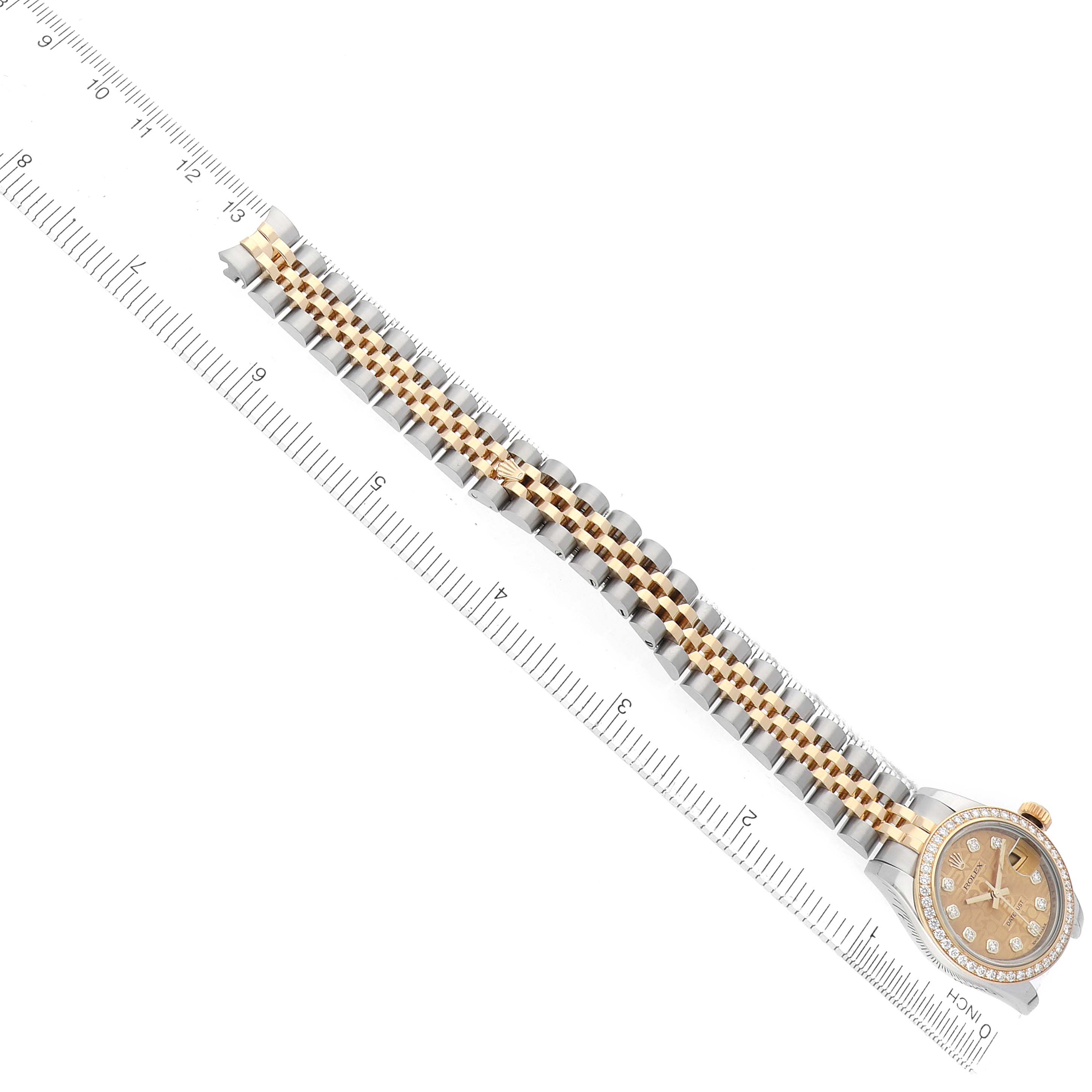 The Rolex Datejust 179383 Women's Steel and Gold (two tone) Champagne Dial watch is shown from a top-down angle, featuring the dial, case, and full bracelet alongside a ruler for scale.