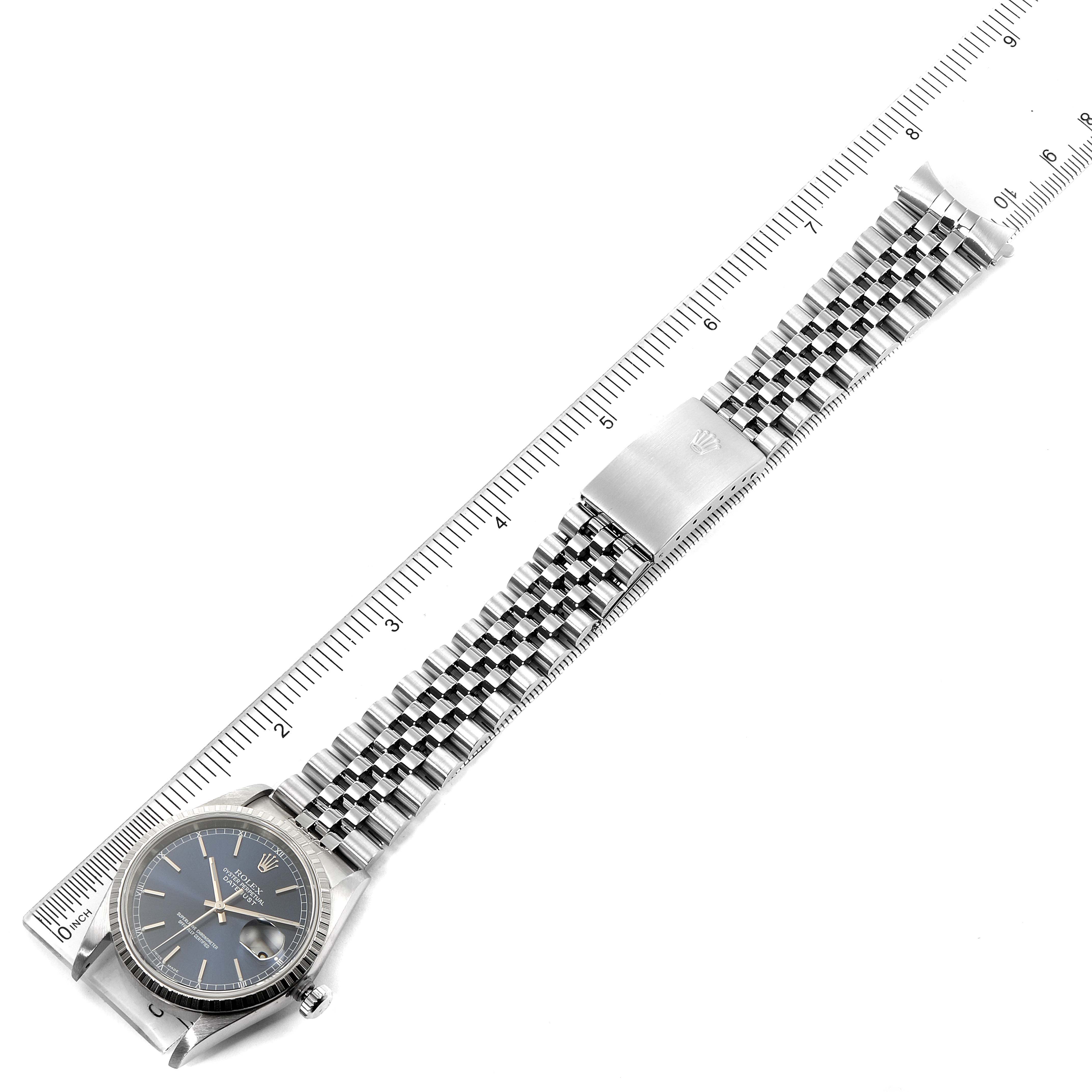 The image shows a top-down view of a Rolex Datejust 16220 Men
s Stainless Steel Blue Dial 16220 Men
s Stainless Steel Blue Dial watch, including its dial, case, jubilee bracelet, and clasp, alongside a ruler.