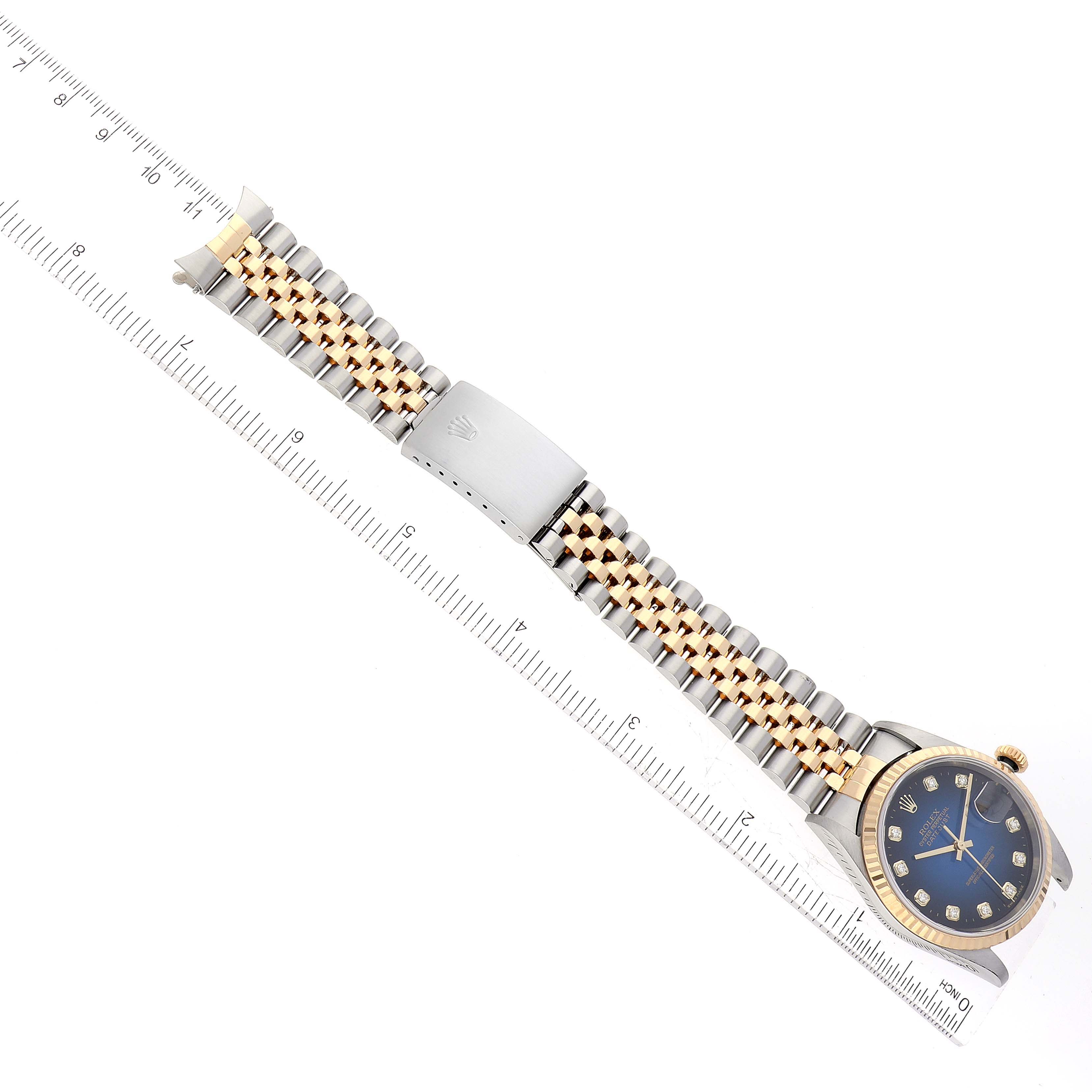 This image shows a Rolex Datejust 16233 Men's Steel and Gold (two tone) Blue Dial 16233 Men's Steel and Gold (two tone) Blue Dial watch laid flat, displaying its face and full two-tone bracelet alongside a ruler.