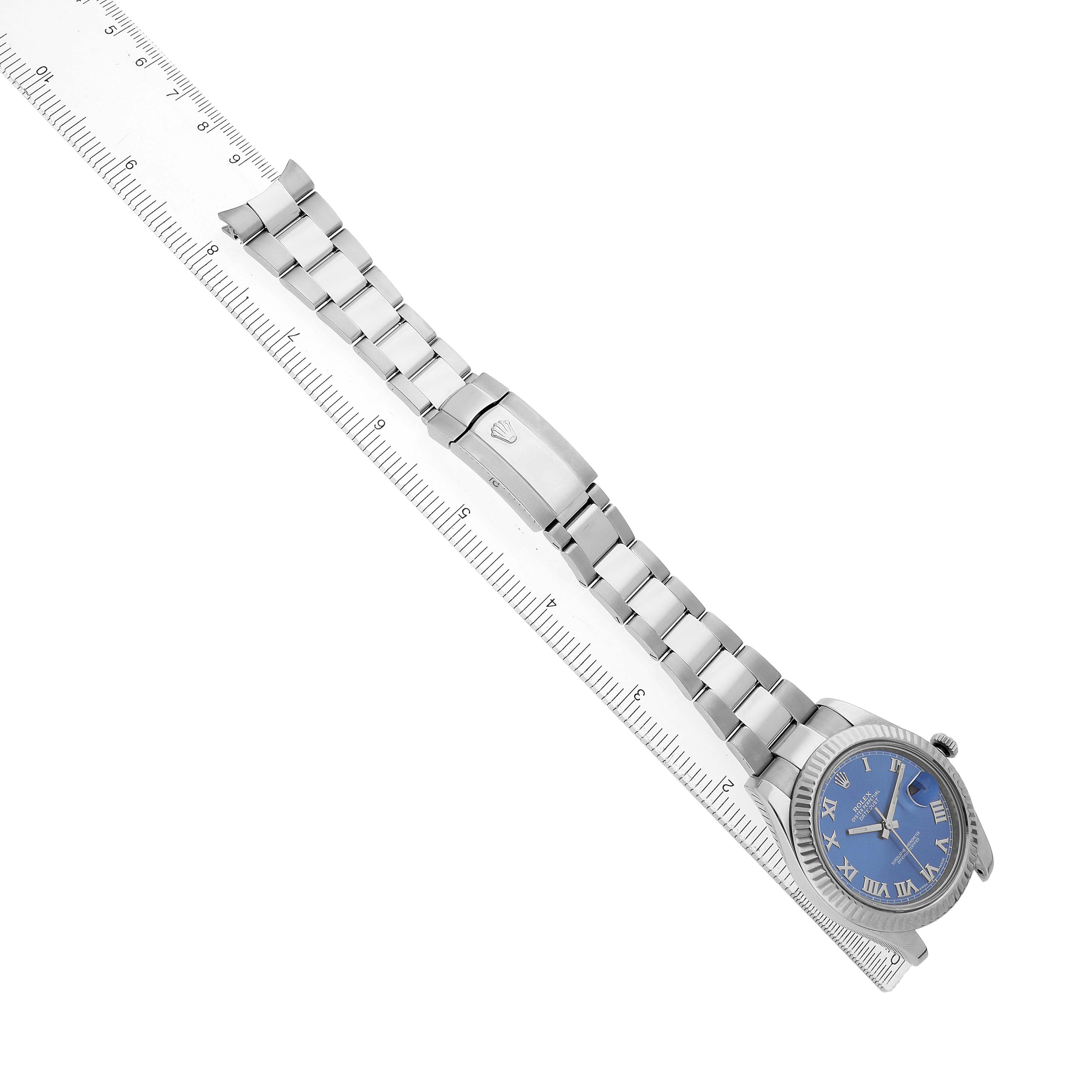 The Rolex Datejust 41 116334 Men's Stainless Steel Blue Dial watch is shown lying diagonally with its bracelet extended alongside a ruler.