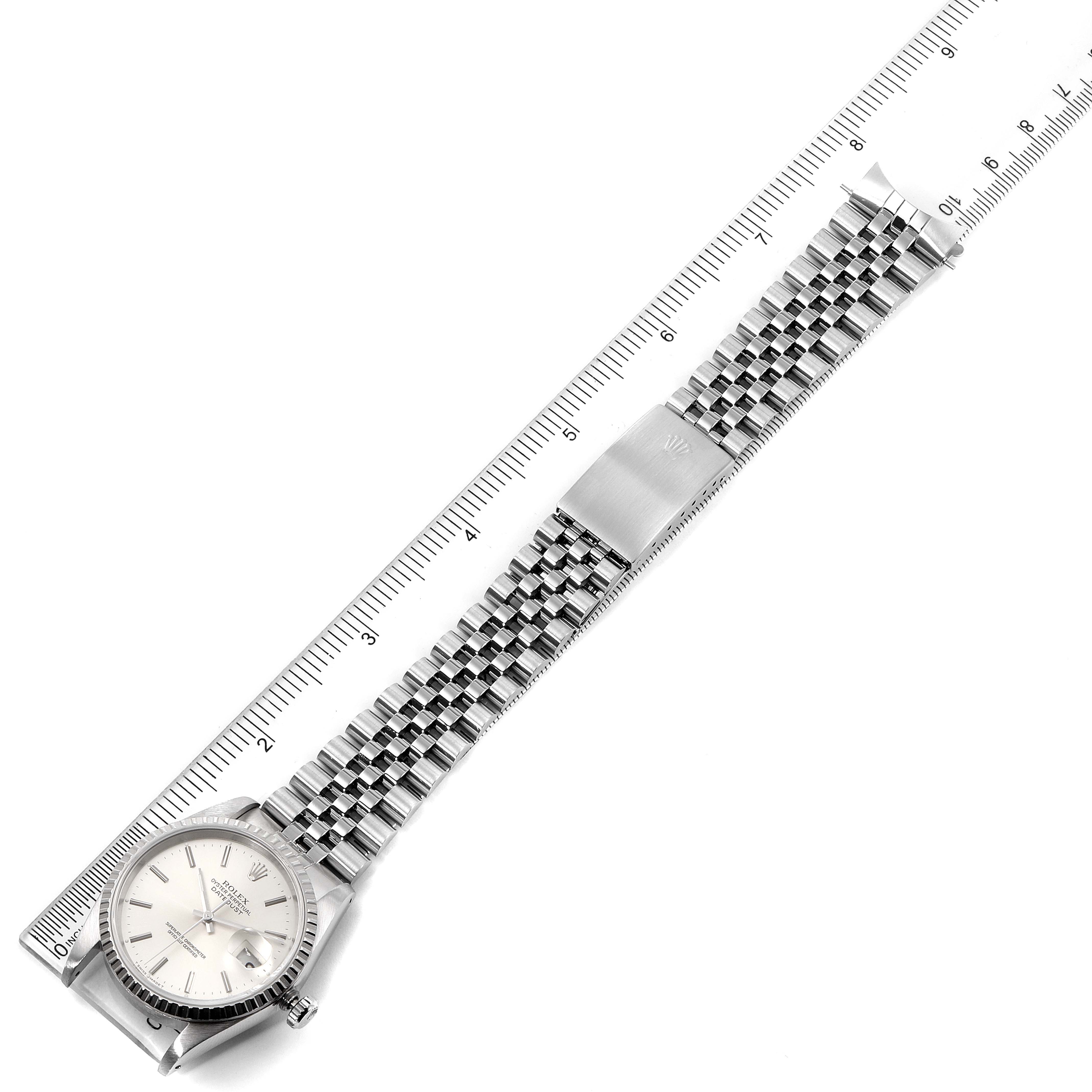 This image shows a Rolex Datejust 16220 Men
s Stainless Steel Silver Dial 16220 Men
s Stainless Steel Silver Dial watch laid flat with its bracelet and clasp extended next to a ruler.