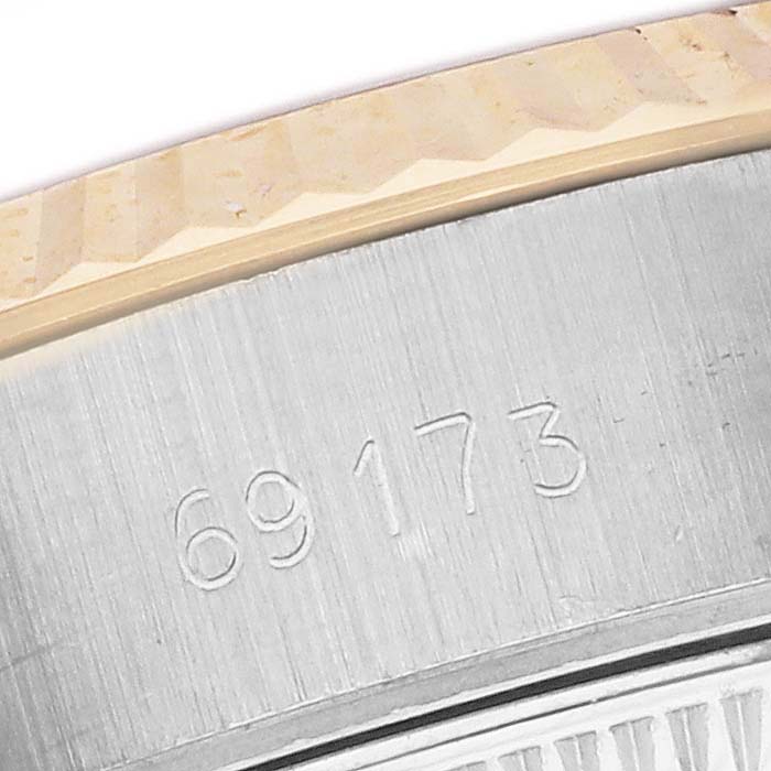 The image shows a close-up of the Rolex Datejust 69173 Women's Steel and Gold (two tone) Champagne Dial model's case with engraved numbers, featuring a partial view of the fluted bezel.