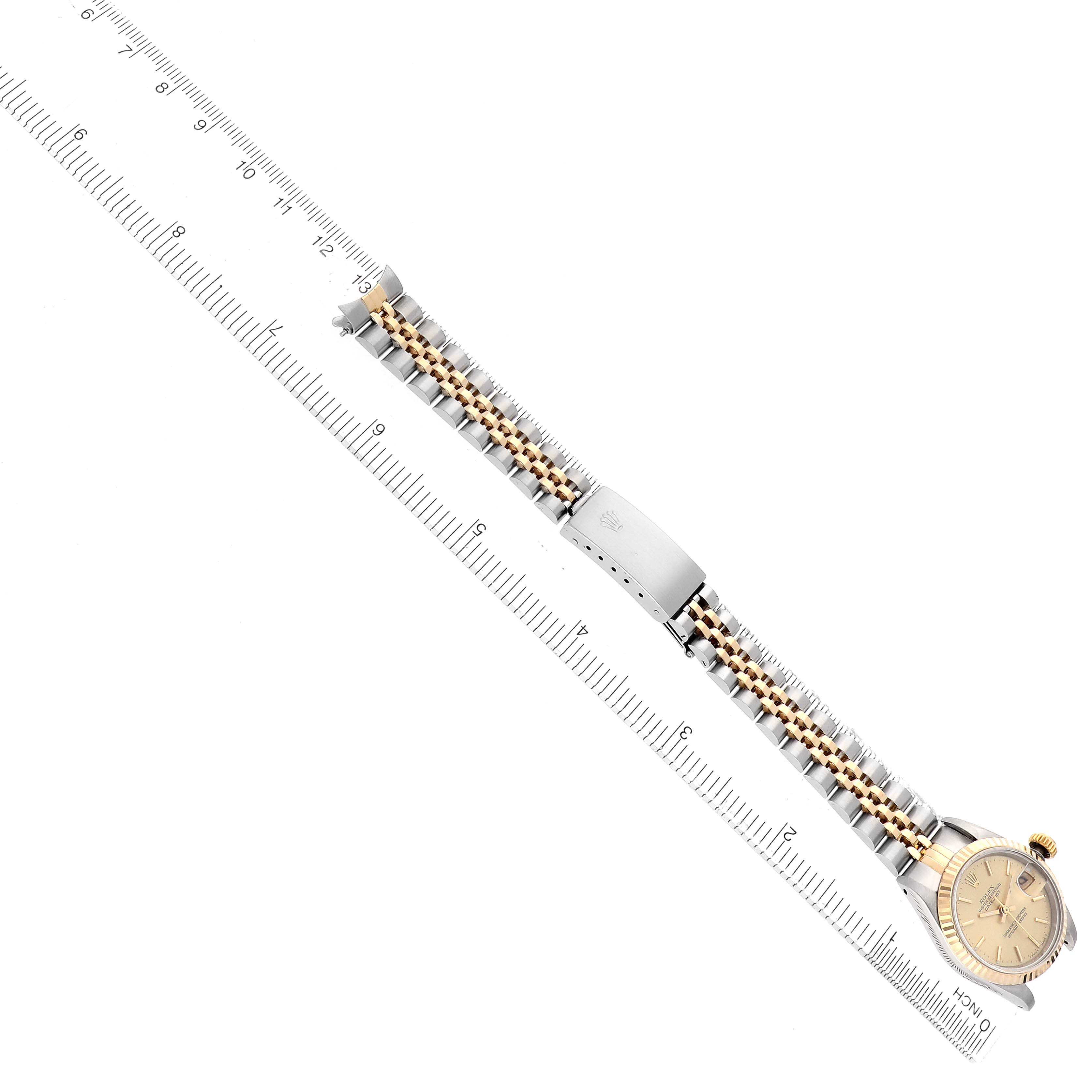 The image shows a Rolex Datejust 69173 Women's Steel and Gold (two tone) Champagne Dial watch laid flat, highlighting the gold and silver bracelet and clasp alongside a ruler for scale.