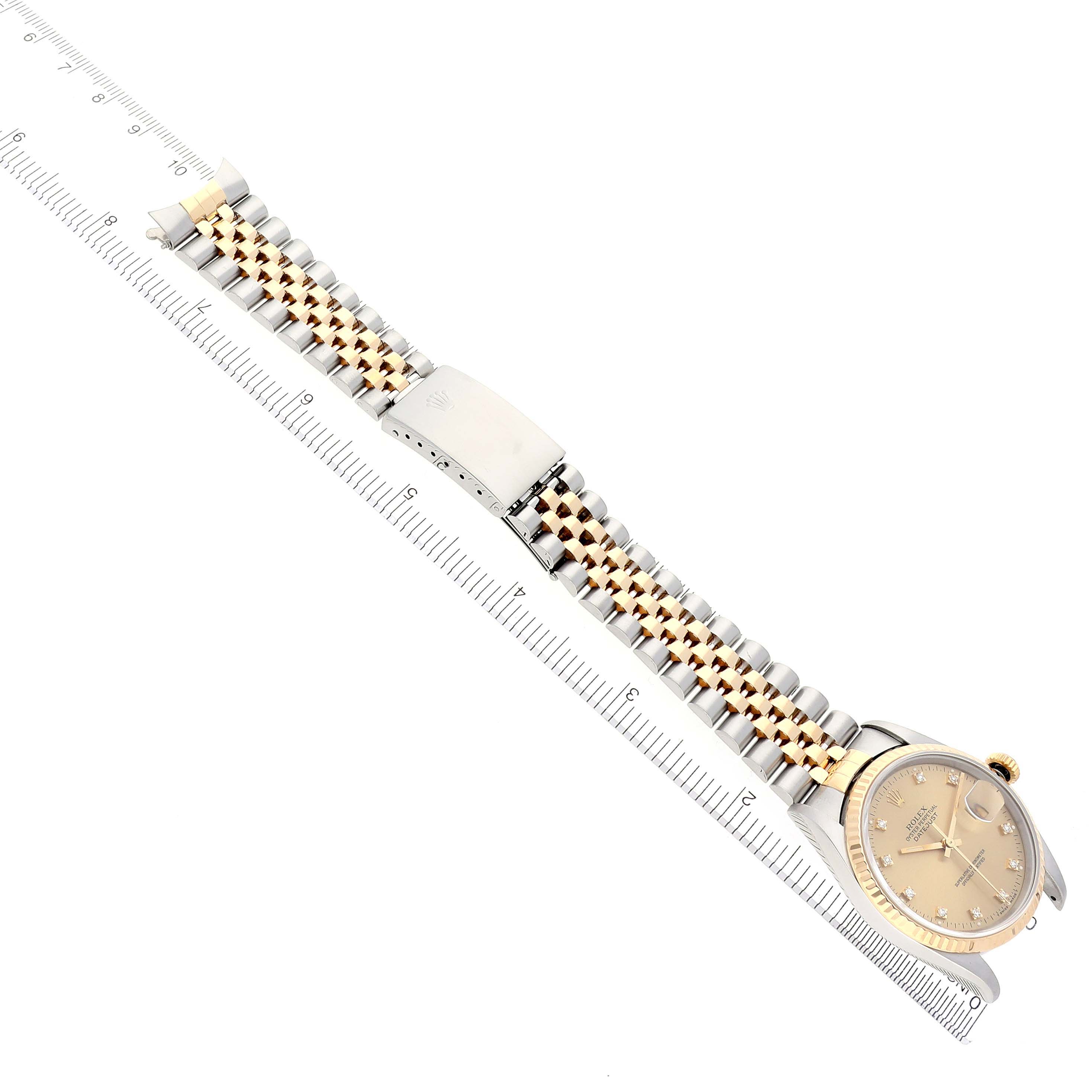 The Rolex Datejust 16233 Men's Steel and Gold (two tone) Champagne Dial 16233 Men's Steel and Gold (two tone) Champagne Dial watch is shown from a top angle, featuring the dial, bracelet, and clasp on a ruler for scale.