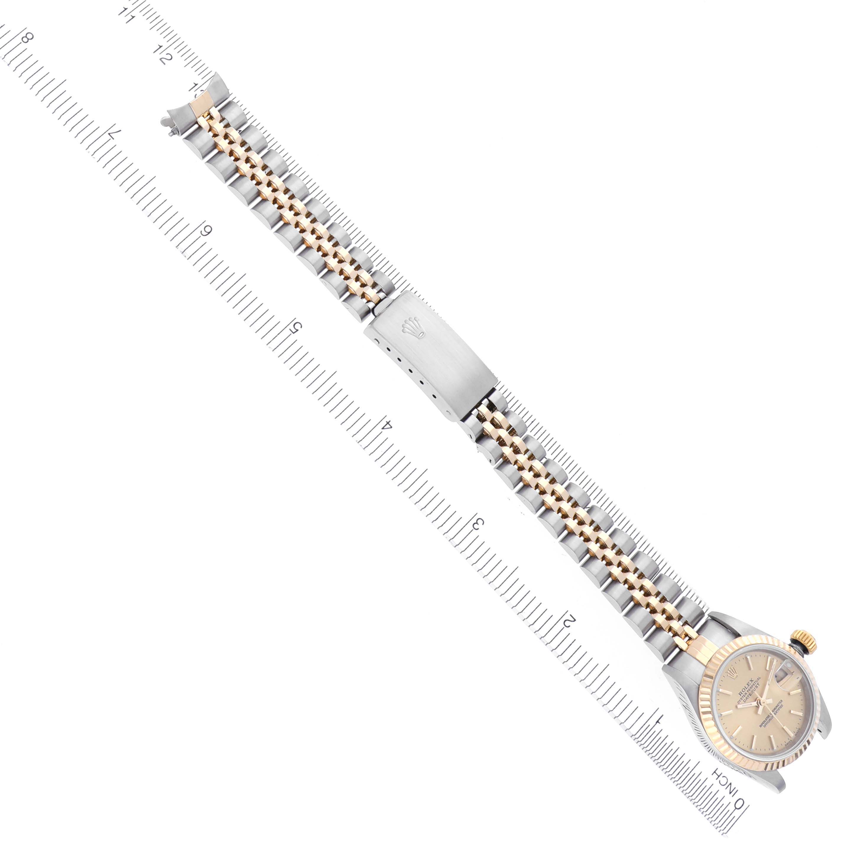 The Rolex Datejust 79173 Women
s Steel and Gold (two tone) Champagne Dial 79173 Women
s Steel and Gold (two tone) Champagne Dial watch is shown from a top view, featuring the face, bezel, and full bracelet alongside a measuring ruler.