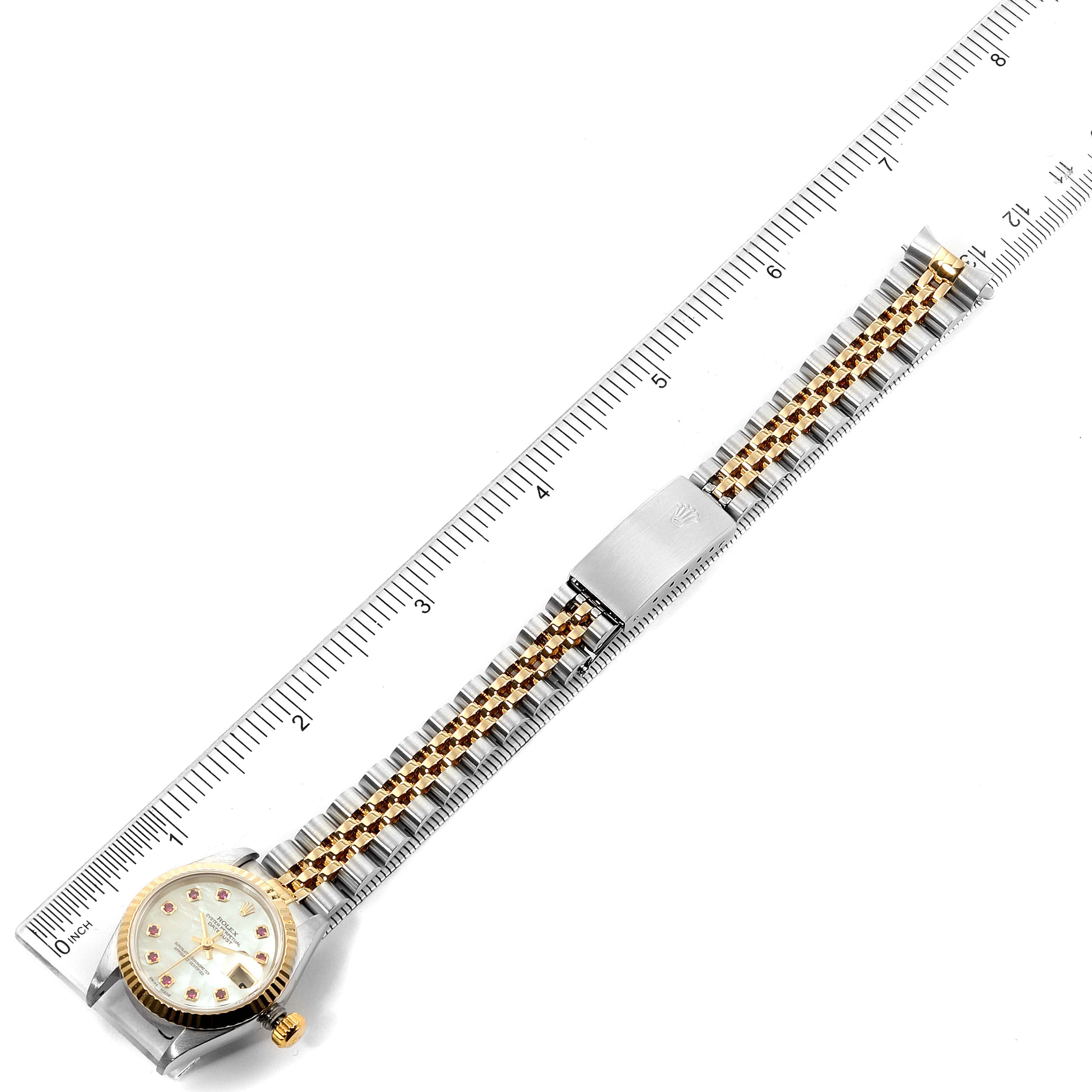 The image displays a Rolex Datejust 79173 Women
s Steel and Gold (two tone) Mother of Pearl Dial 79173 Women
s Steel and Gold (two tone) Mother of Pearl Dial watch laid flat from an aerial angle, alongside a ruler for scale reference.