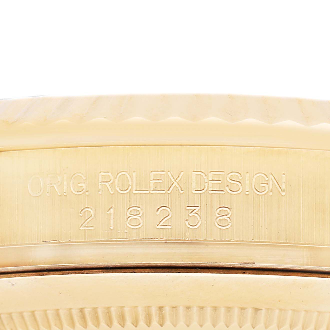 The image shows a close-up of the case side of a Rolex President 218238 Men's Yellow Gold Champagne Dial, focusing on the engraved model number and design text.
