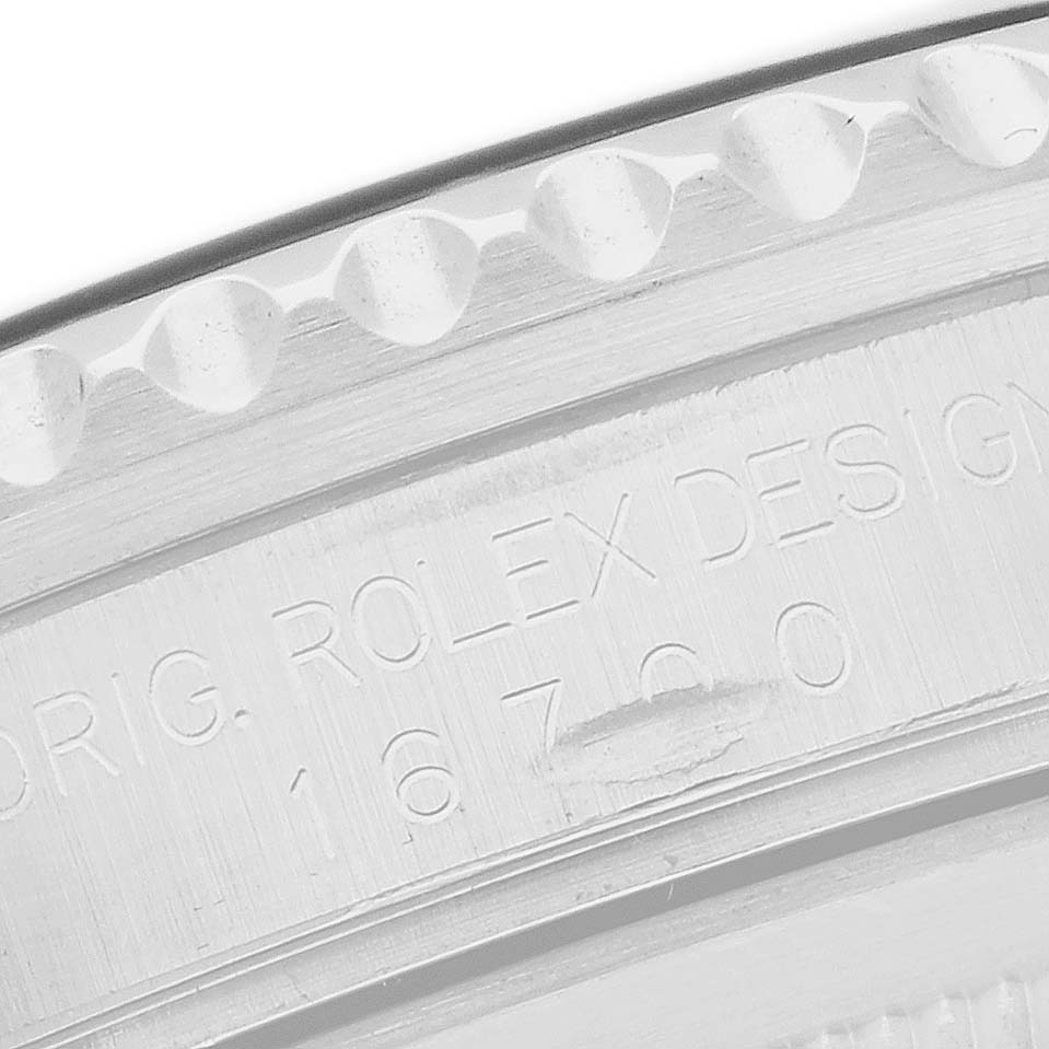 The image shows a close-up of the engraved side of a Rolex GMT-Master 16700 Men's Stainless Steel Black Dial watch case with model details.