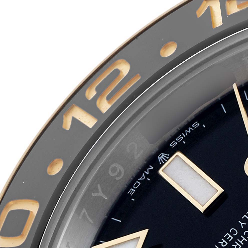 The image shows a close-up of the Rolex GMT-Master 126713 Men's Steel and Gold (two tone) Black Dial watch bezel and part of its dial, highlighting the 12-hour marker.