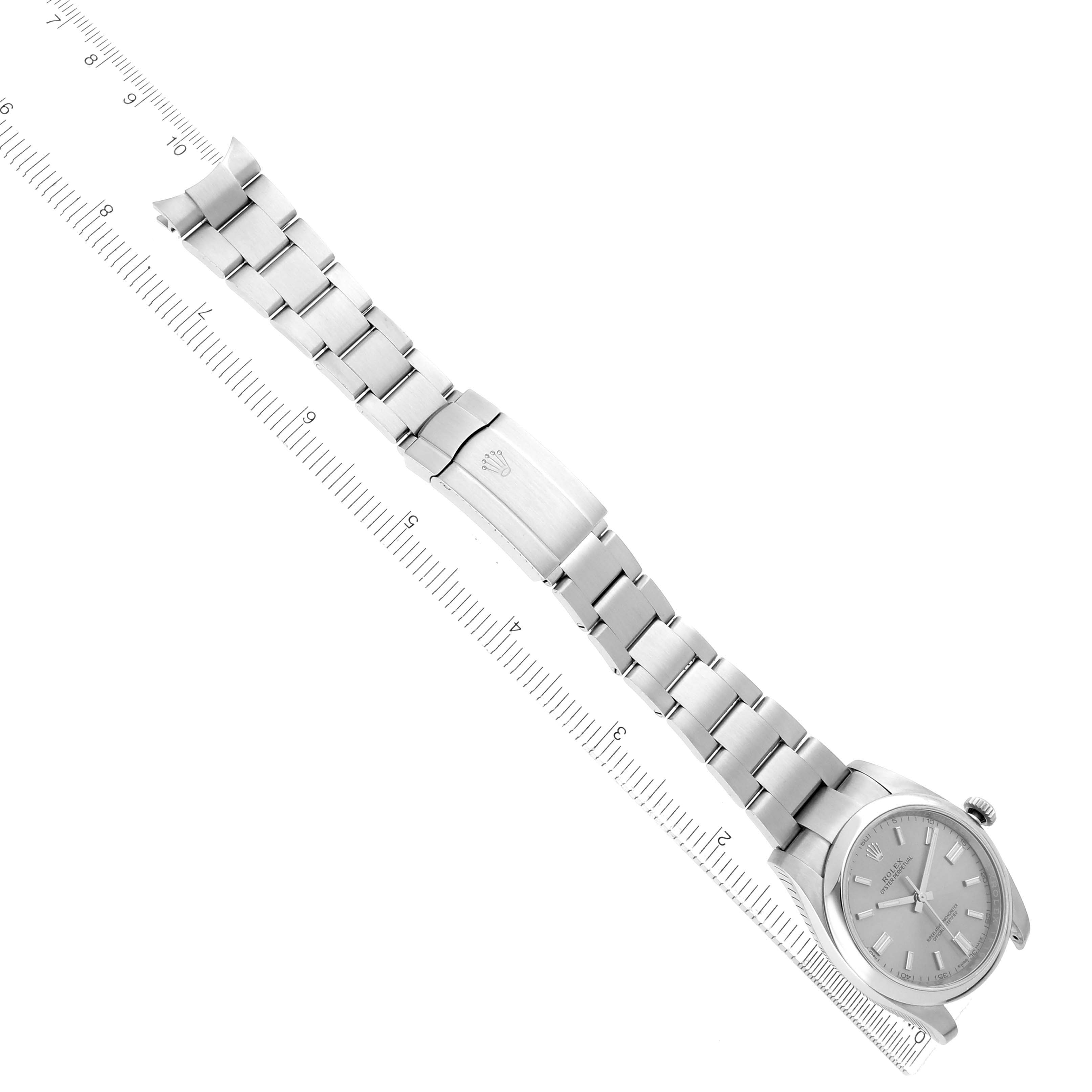 The Oyster Perpetual by Rolex is shown at an angle displaying the full bracelet, clasp, and face, aligned beside a ruler.