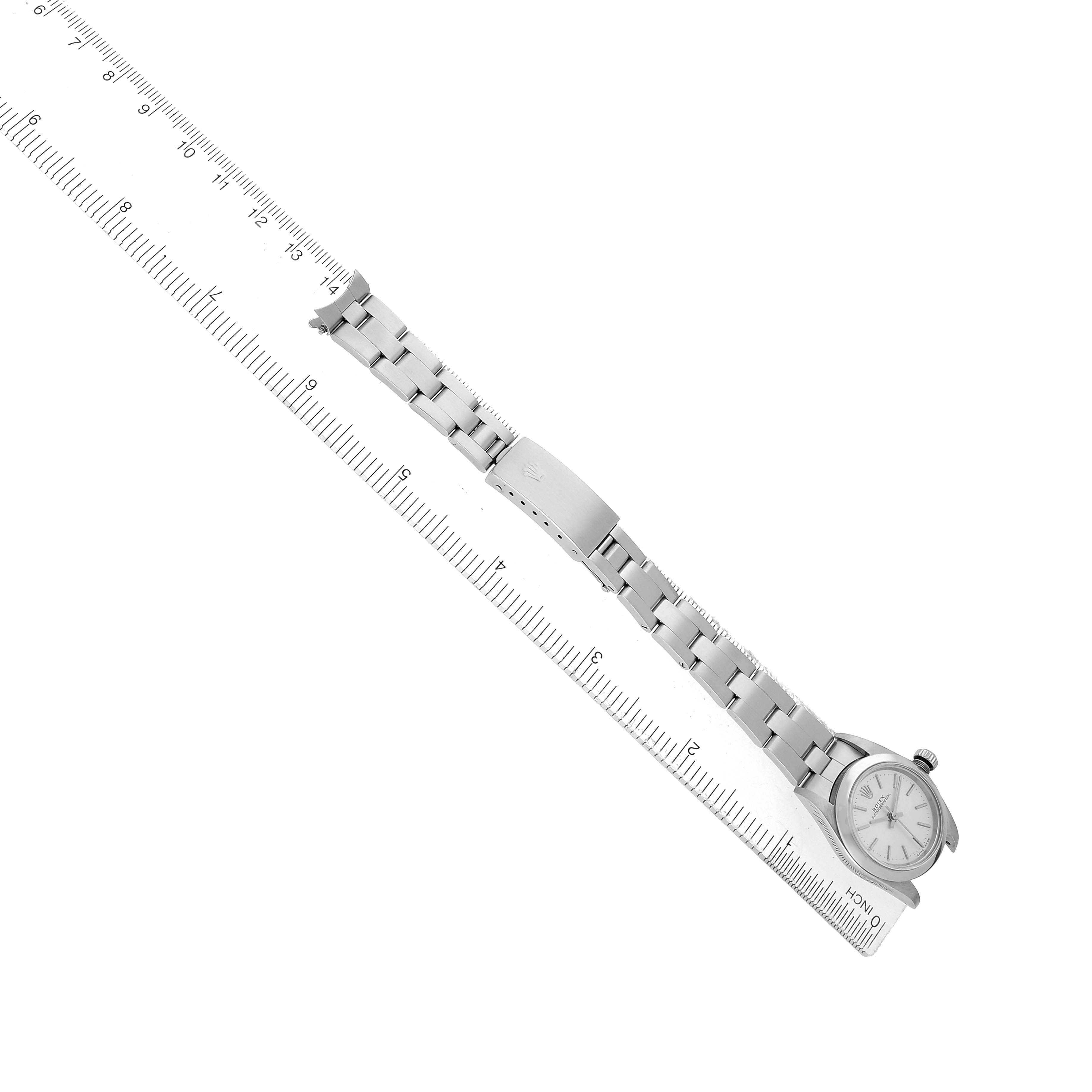 The Rolex Oyster Perpetual 76080 Women's Stainless Steel Silver Dial watch is shown from a top-down angle, displayed alongside a ruler to showcase its full bracelet length.