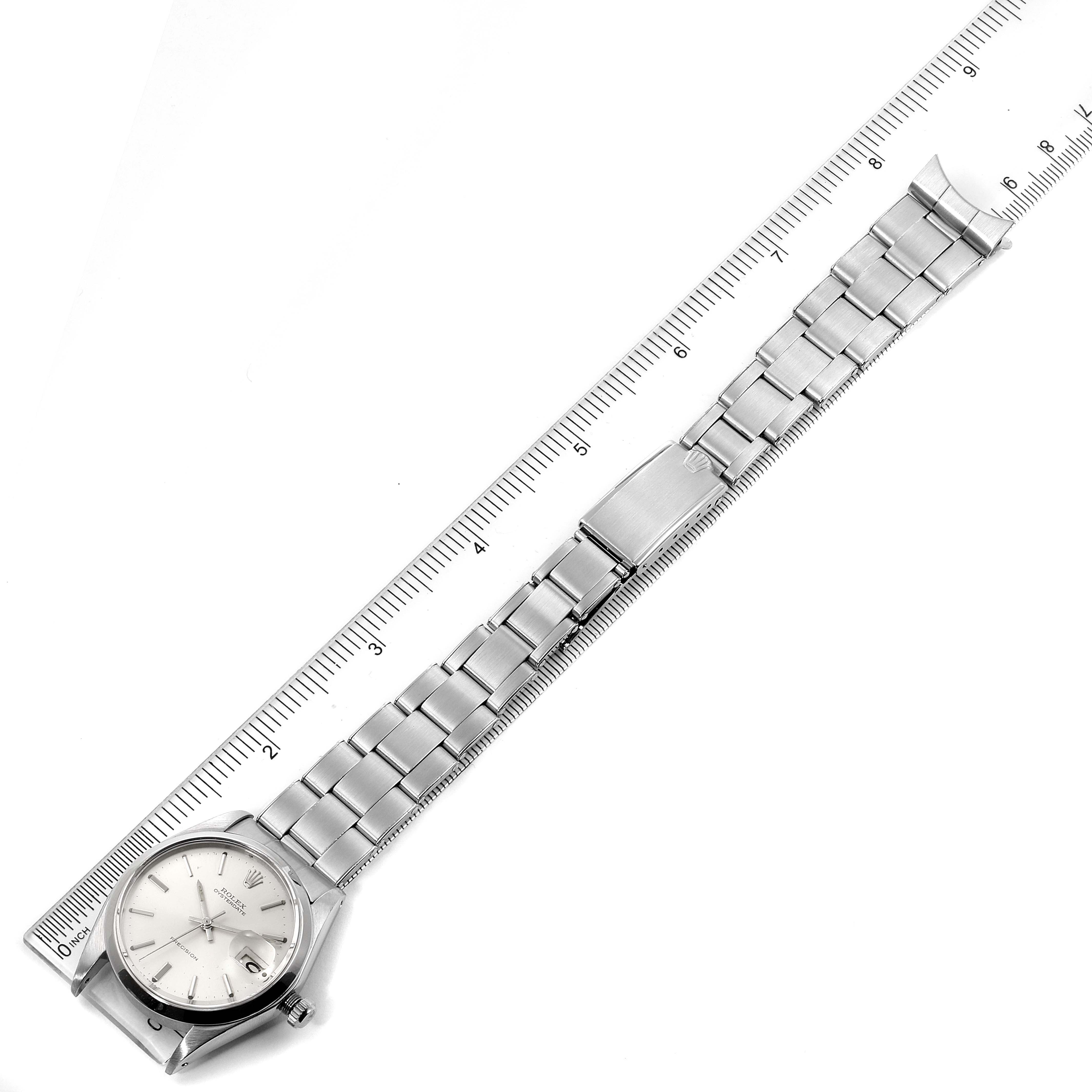 The image shows a top-down view of a Rolex Vintage Collection 6694 Men
s Stainless Steel Silver Dial 6694 Men
s Stainless Steel Silver Dial watch, displaying its face, bracelet, and a ruler for scale.