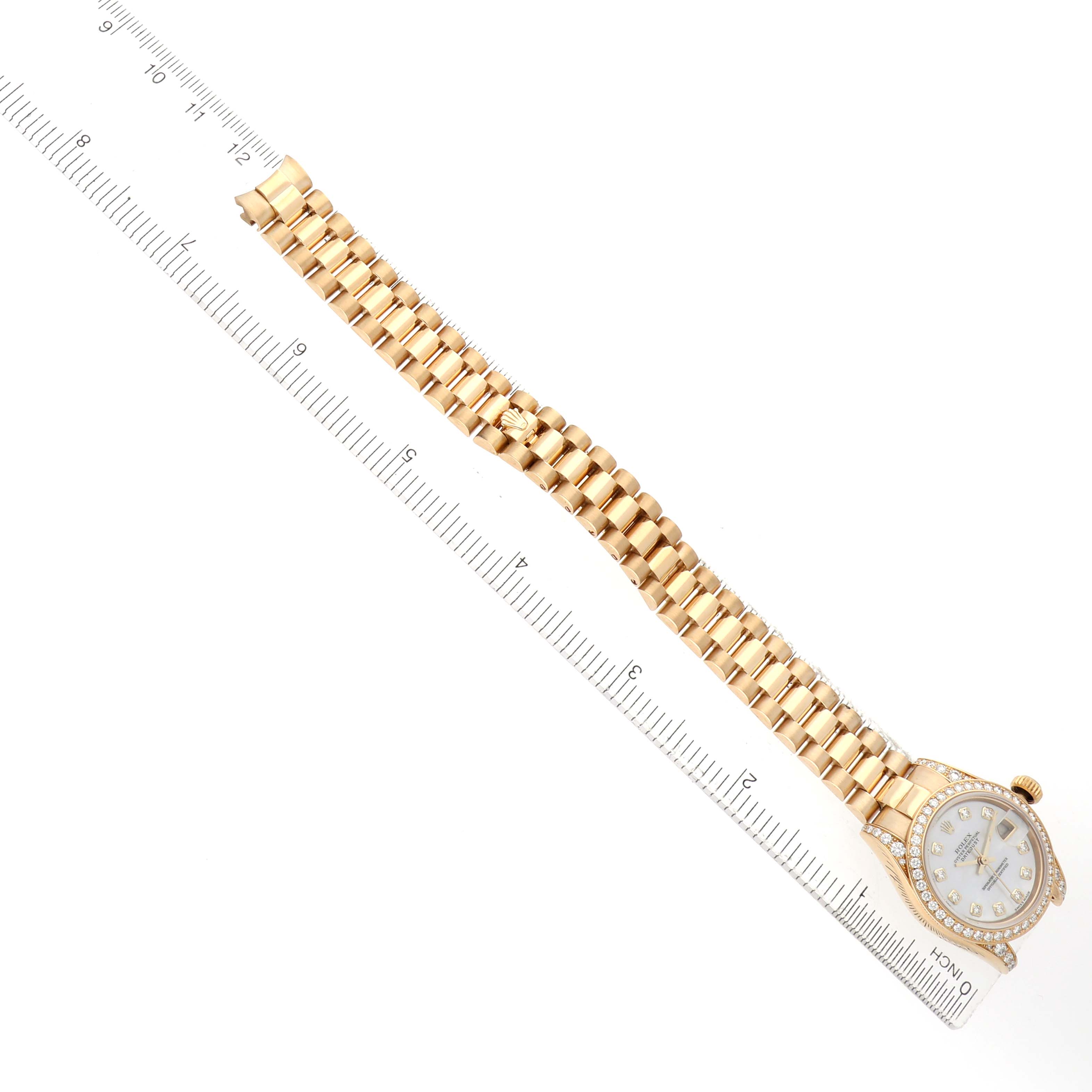 The Rolex President 179158 Women's Yellow Gold Mother of Pearl Dial watch is shown from a top-down angle, highlighting the bracelet and face alongside a ruler.