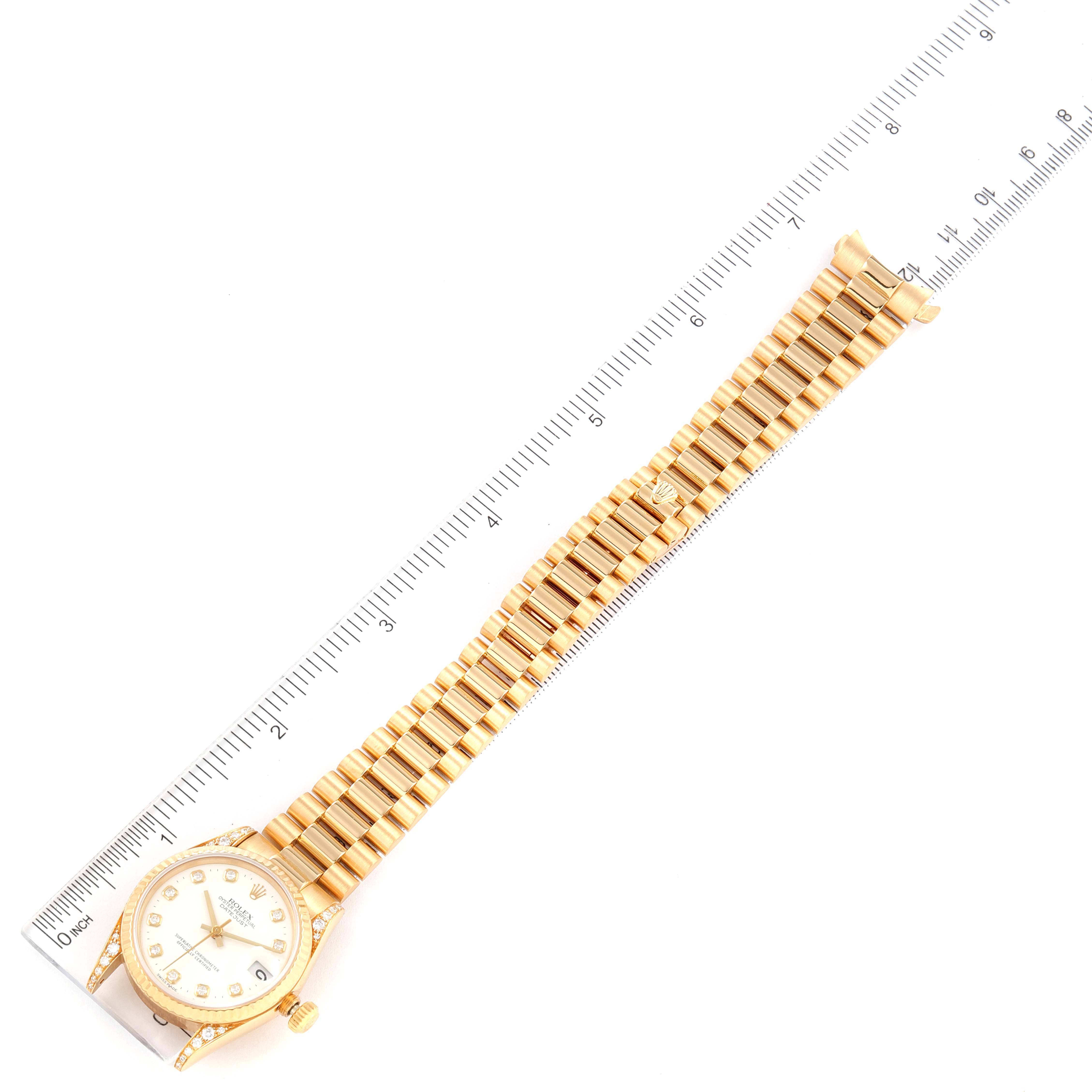 The image shows an overhead view of a Rolex President 68238 Women's Yellow Gold White Dial 68238 Women's Yellow Gold White Dial model watch, including its face and gold band, placed next to a ruler for measurement.
