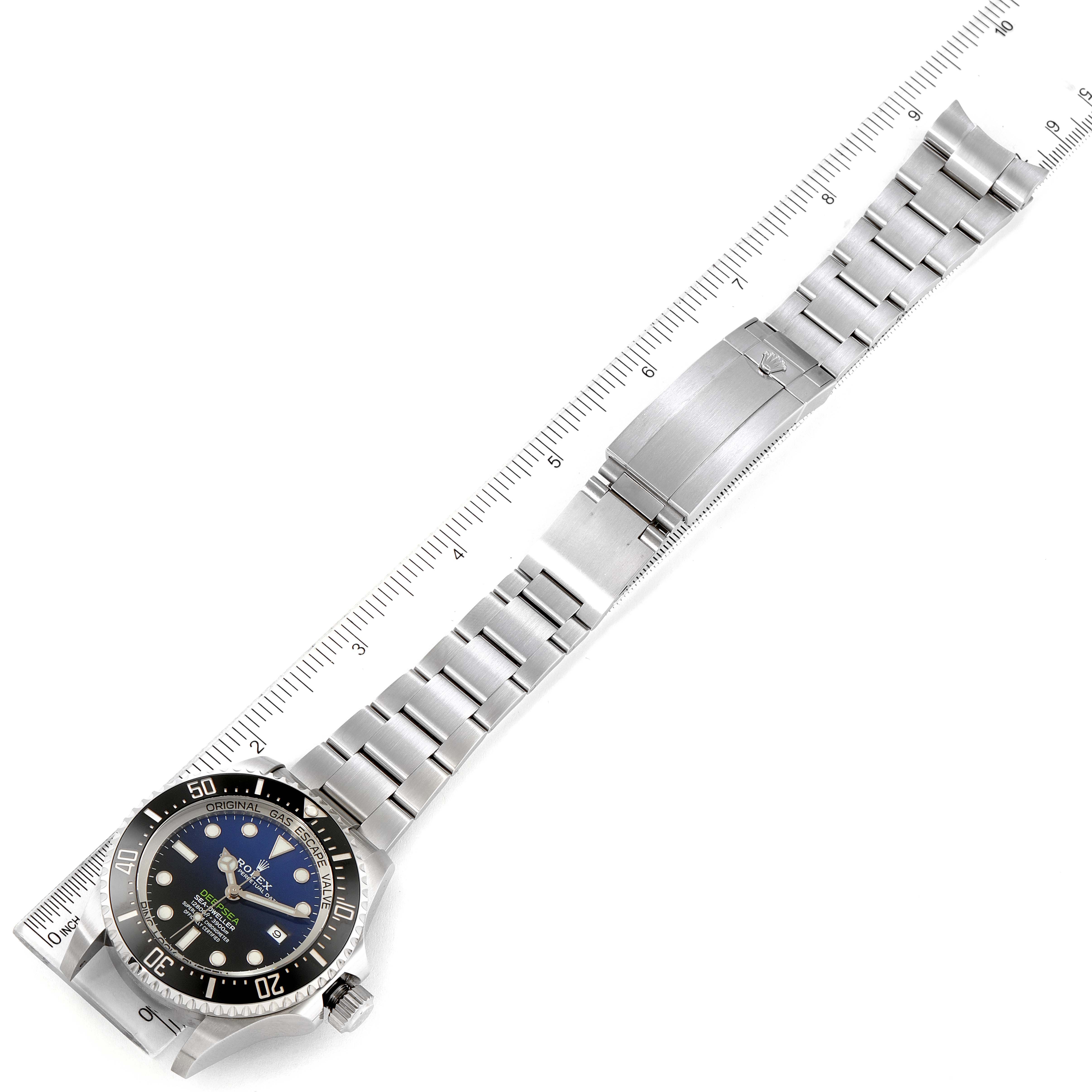 The image shows the Rolex Sea-Dweller 126660 Men
s Stainless Steel Blue Dial 126660 Men
s Stainless Steel Blue Dial watch horizontally, showcasing its face, bezel, and entire metal bracelet with a ruler for scale.