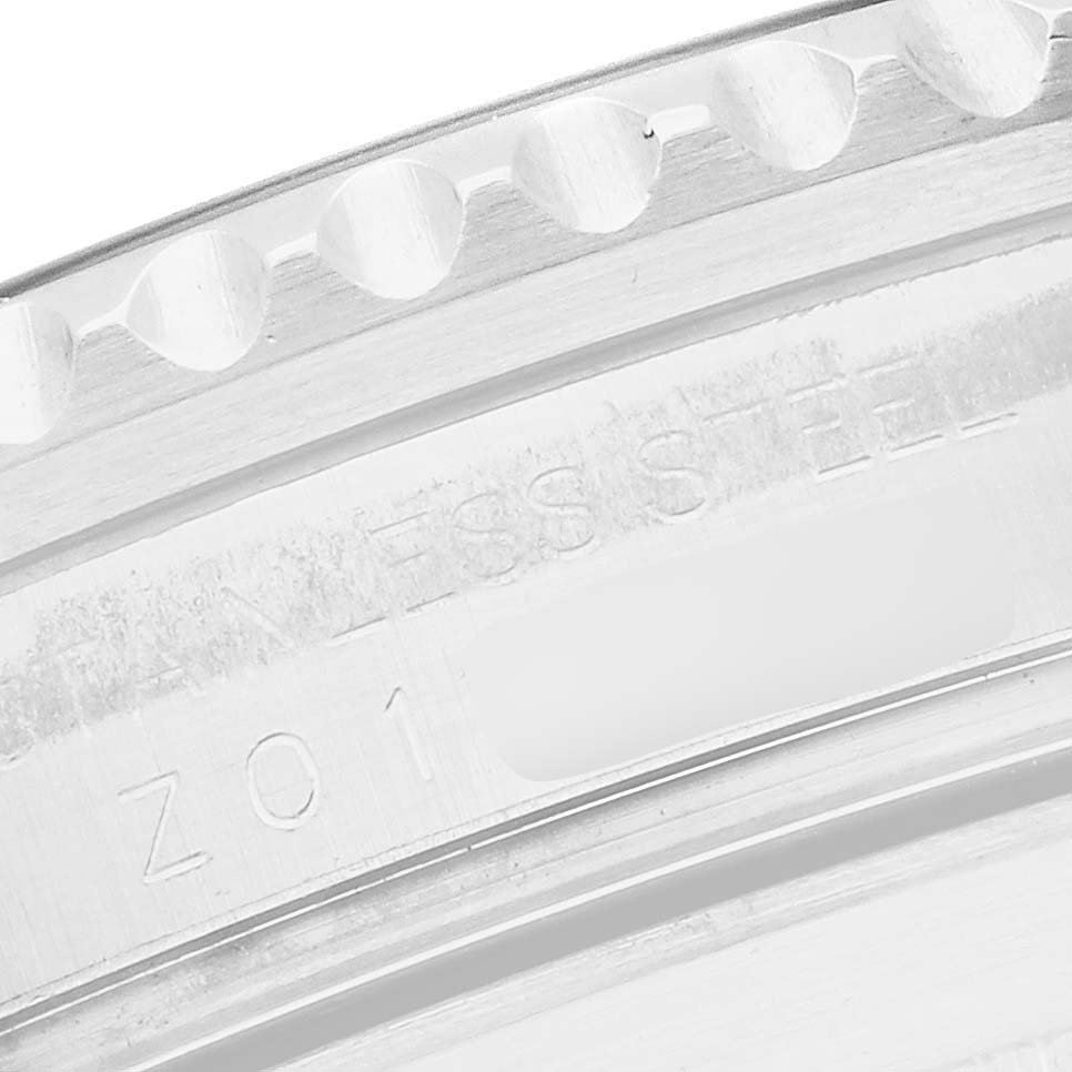 The image shows a close-up of the edge of a Rolex Submariner 16610 Men's Stainless Steel Black Dial's bezel, focusing on the engraved "STAINLESS STEEL."