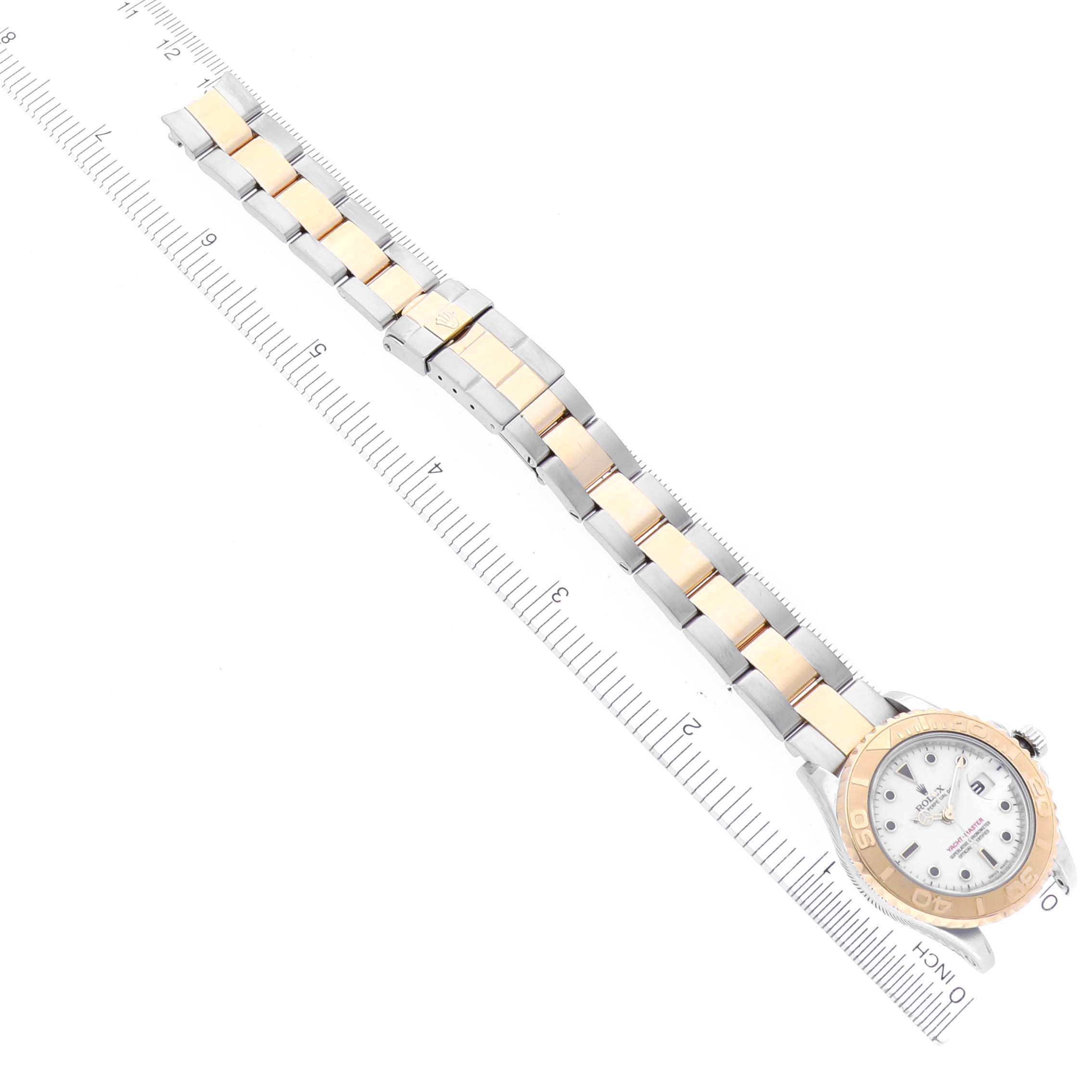 The Rolex Yacht-Master 169623 Women
s Steel and Gold (two tone) White Dial 169623 Women
s Steel and Gold (two tone) White Dial watch is shown from a top view, highlighting the full bracelet and watch face alongside a ruler.