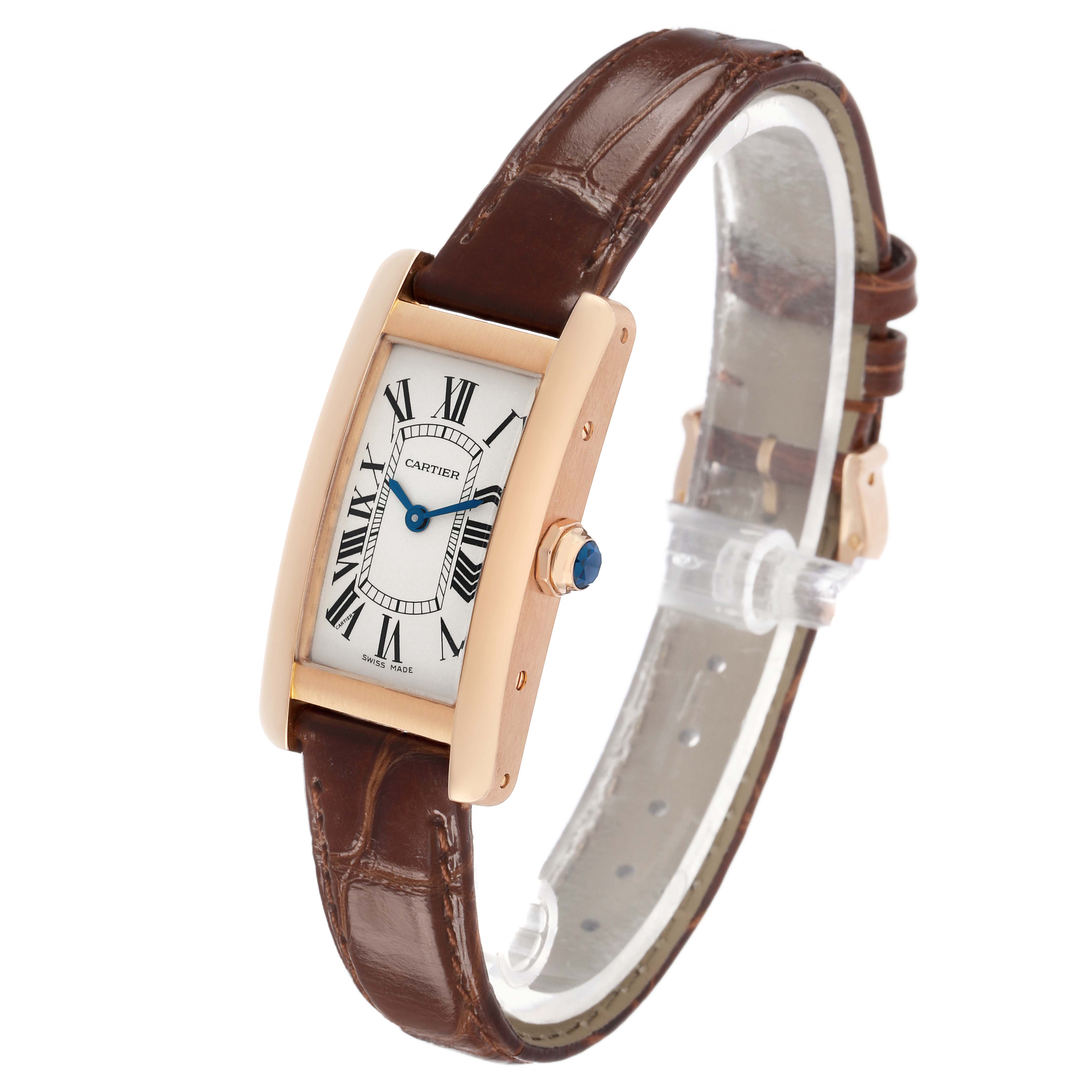 The Cartier Tank Americaine W2607456 Women's Rose Gold Silver Dial watch is shown at a three-quarter angle, displaying its rectangular face, crown with a blue cabochon, and brown leather strap.