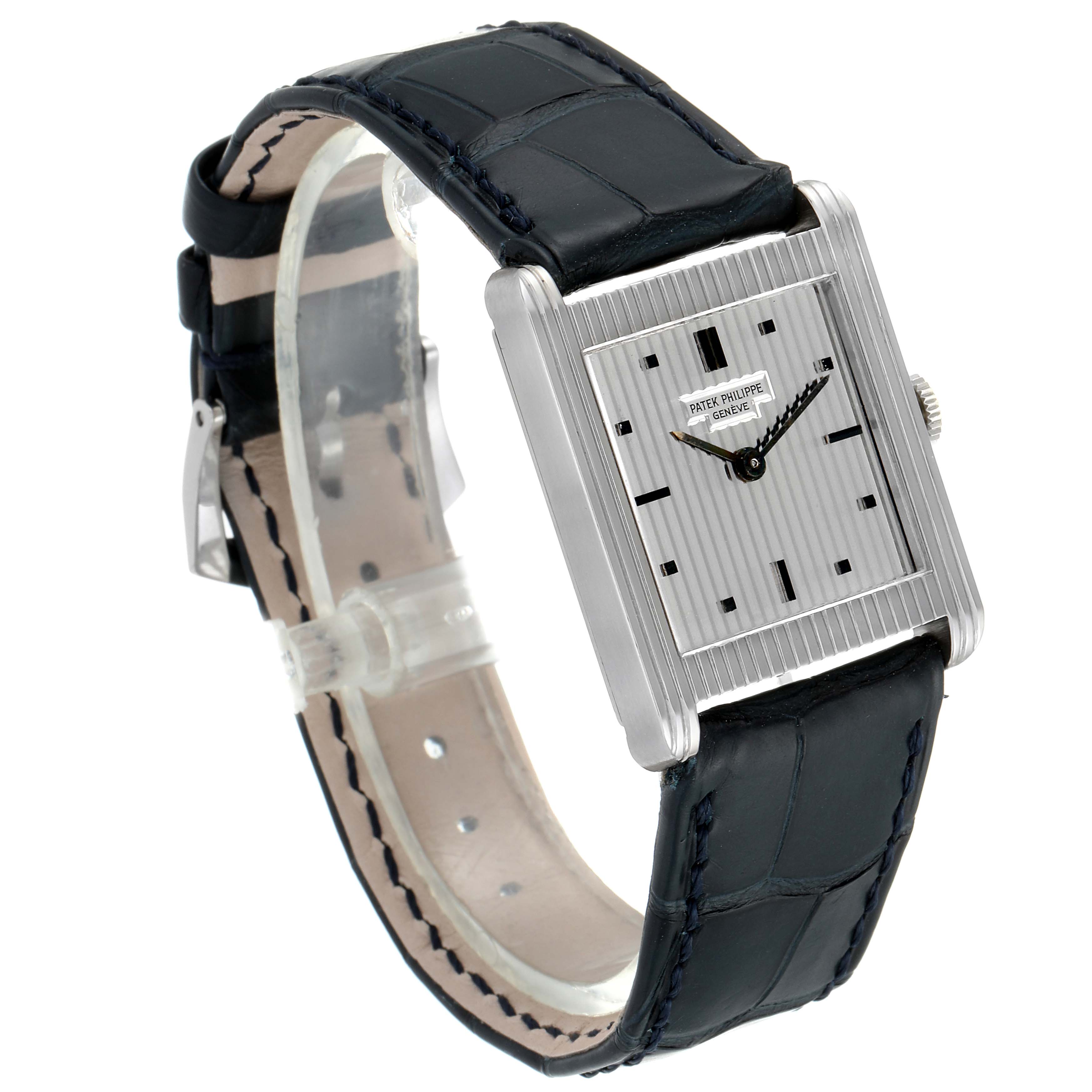 The image shows a vintage Patek Philippe watch in an angled view, highlighting its rectangular face, silver dial, and black leather strap.