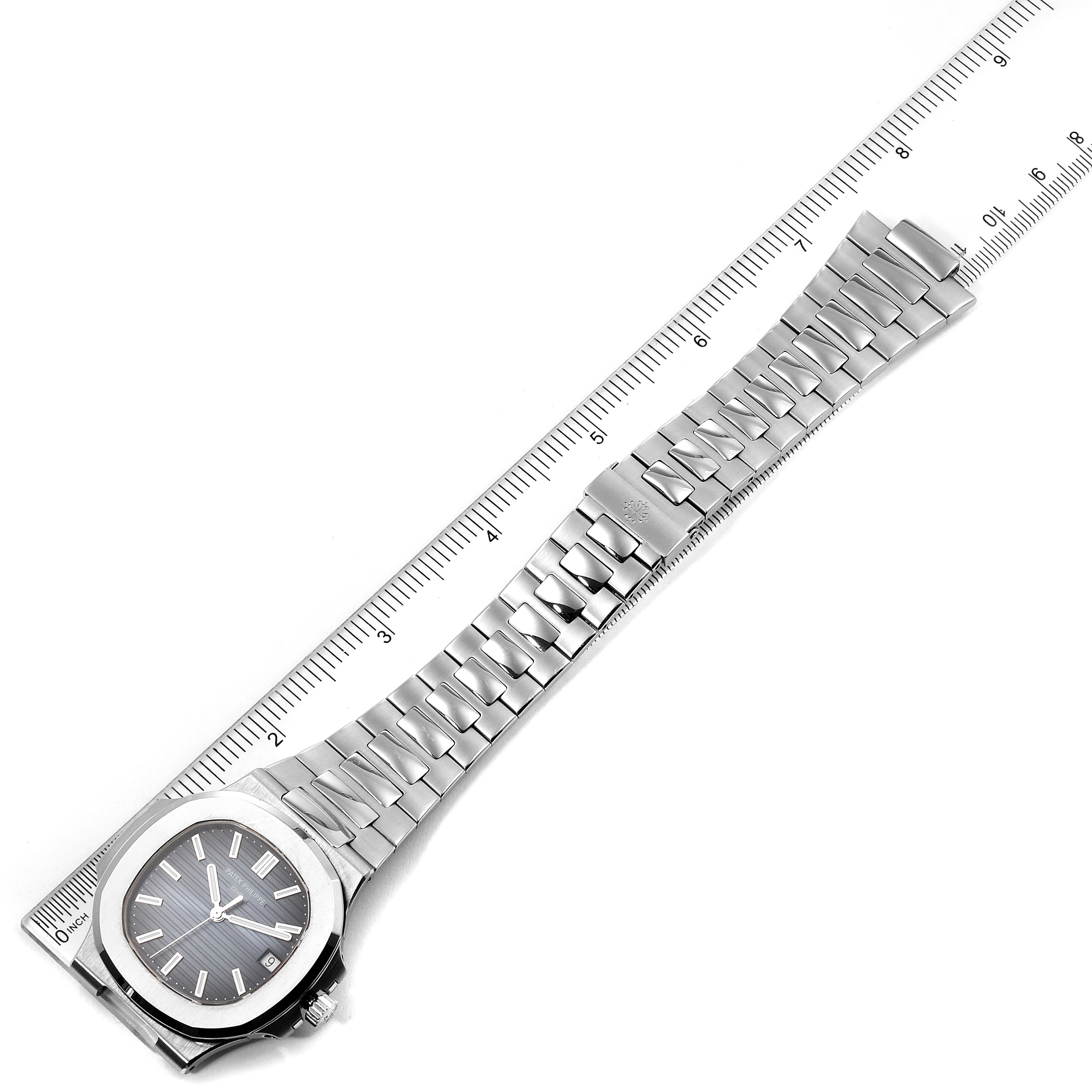 The image shows a top view of the Patek Philippe Nautilus 5711/1A-010 Men's Stainless Steel Blue Dial 5711/1A-010 Men's Stainless Steel Blue Dial watch, highlighting its dial, bracelet, and clasp, alongside a ruler for scale.