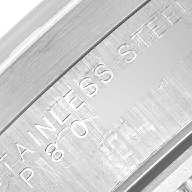 The image shows a close-up of the engraved stainless steel part of a Rolex Date 15210 Men's Stainless Steel Blue Dial 15210 Men's Stainless Steel Blue Dial watch.