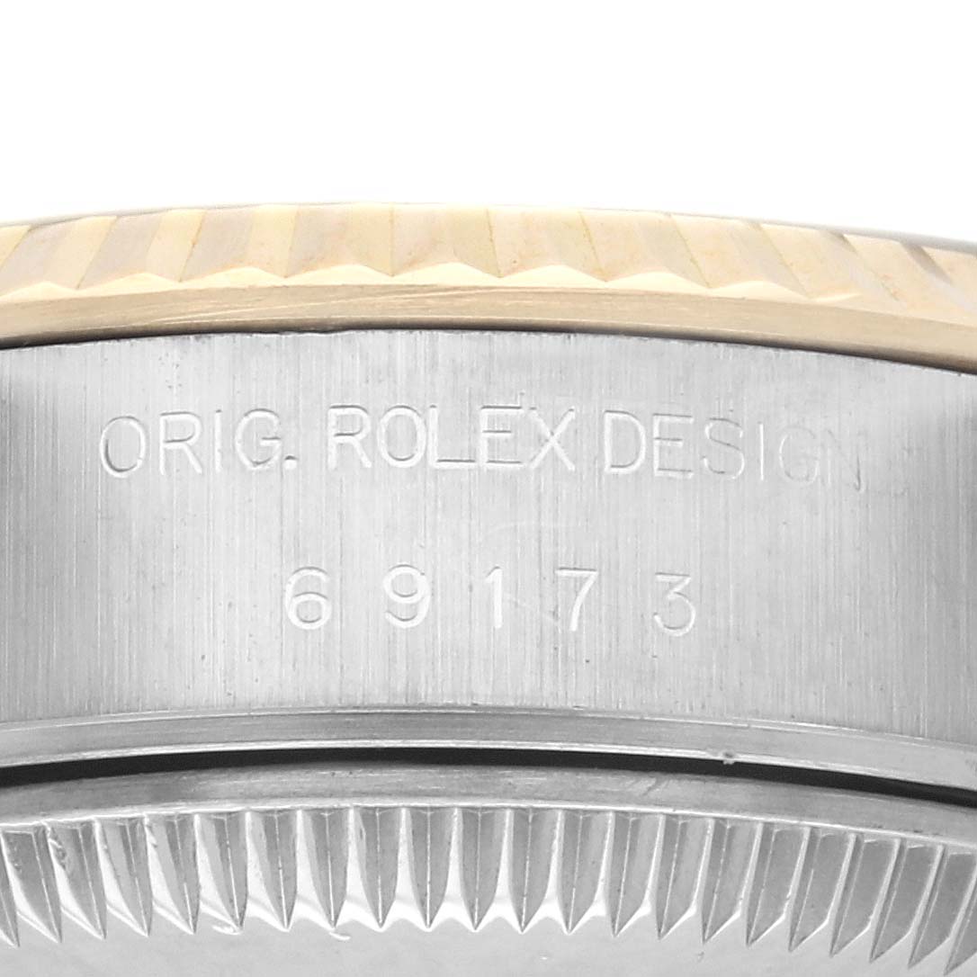 The image shows a close-up of the Rolex Datejust 69173 Women
s Steel and Gold (two tone) Champagne Dial 69173 Women
s Steel and Gold (two tone) Champagne Dial model
s side, highlighting the case and some engravings.