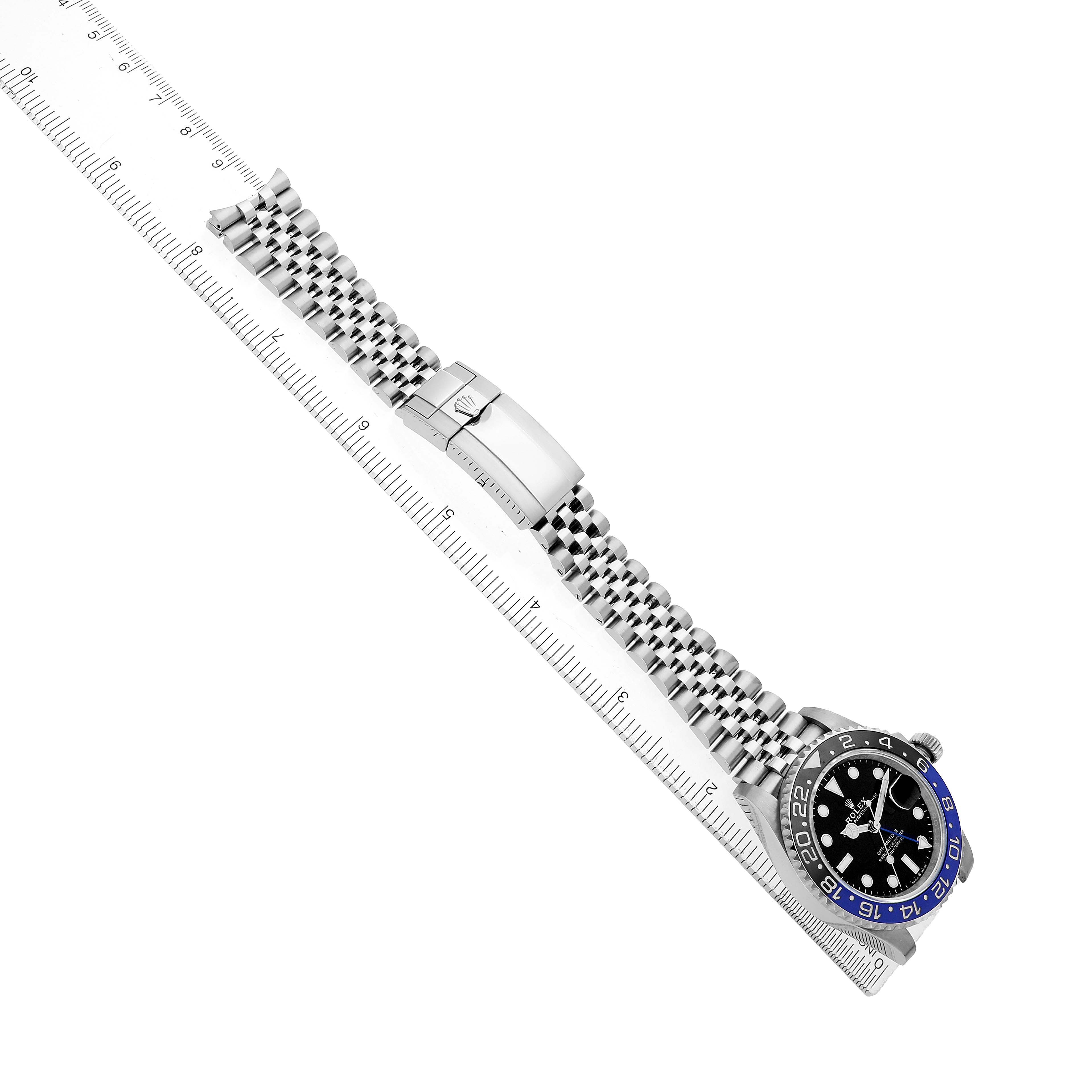 The Rolex GMT-Master 126710BLNR Men's Stainless Steel Black Dial watch is shown at an angled top-down view, highlighting the bezel, face, and bracelet clasp alongside a ruler.
