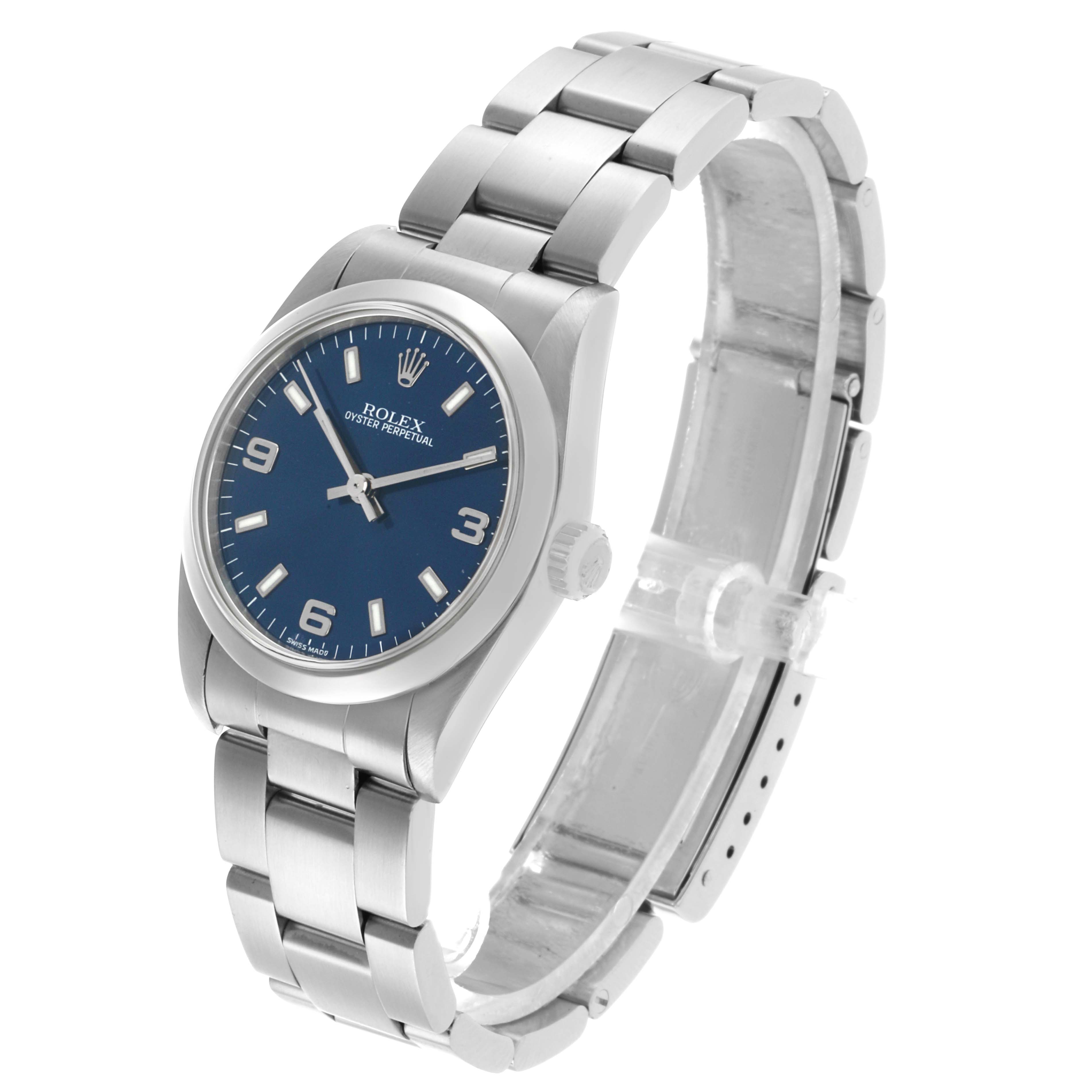 The Rolex Oyster Perpetual 77080 Women's Stainless Steel Blue Dial watch is shown from an angled side view, displaying the face, bezel, lugs, and bracelet.