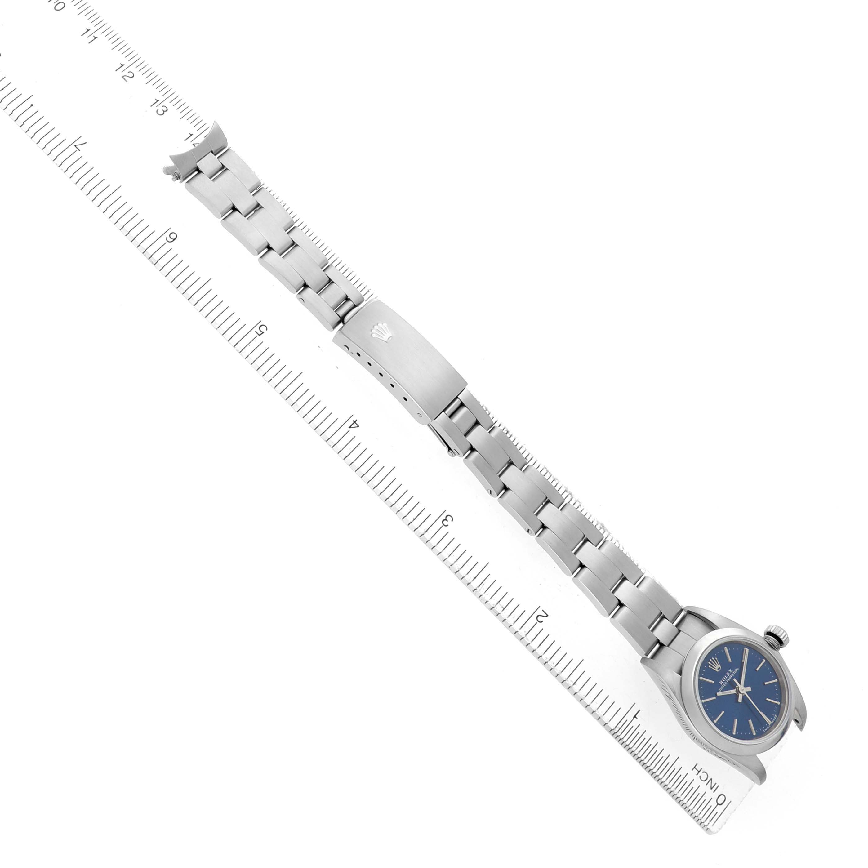 The Rolex Oyster Perpetual 76080 Women's Stainless Steel Blue Dial watch is shown from a top view, highlighting the bracelet, case, and clasp alongside a ruler.