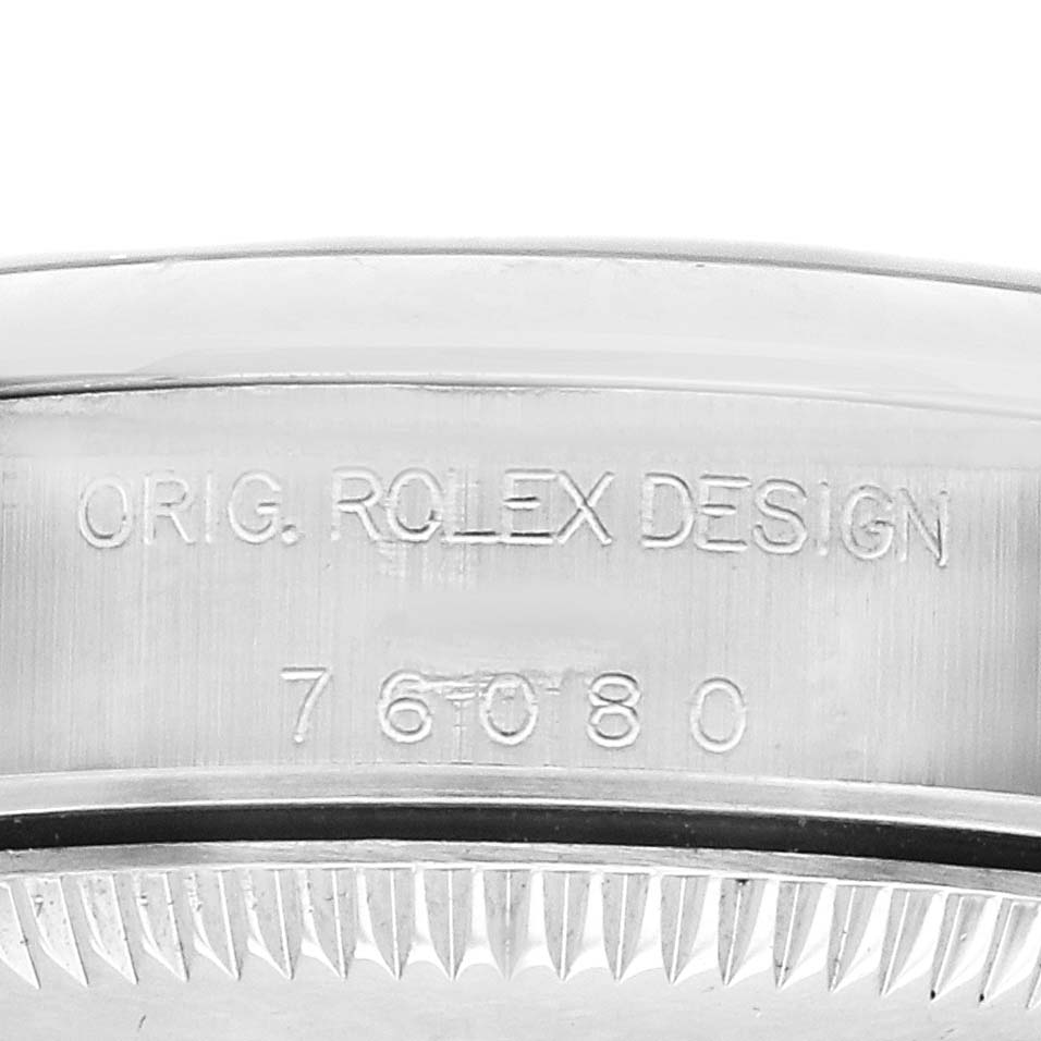 The image shows the edge of the Rolex Oyster Perpetual 76080 Women's Stainless Steel Blue Dial watch case with engraving details.