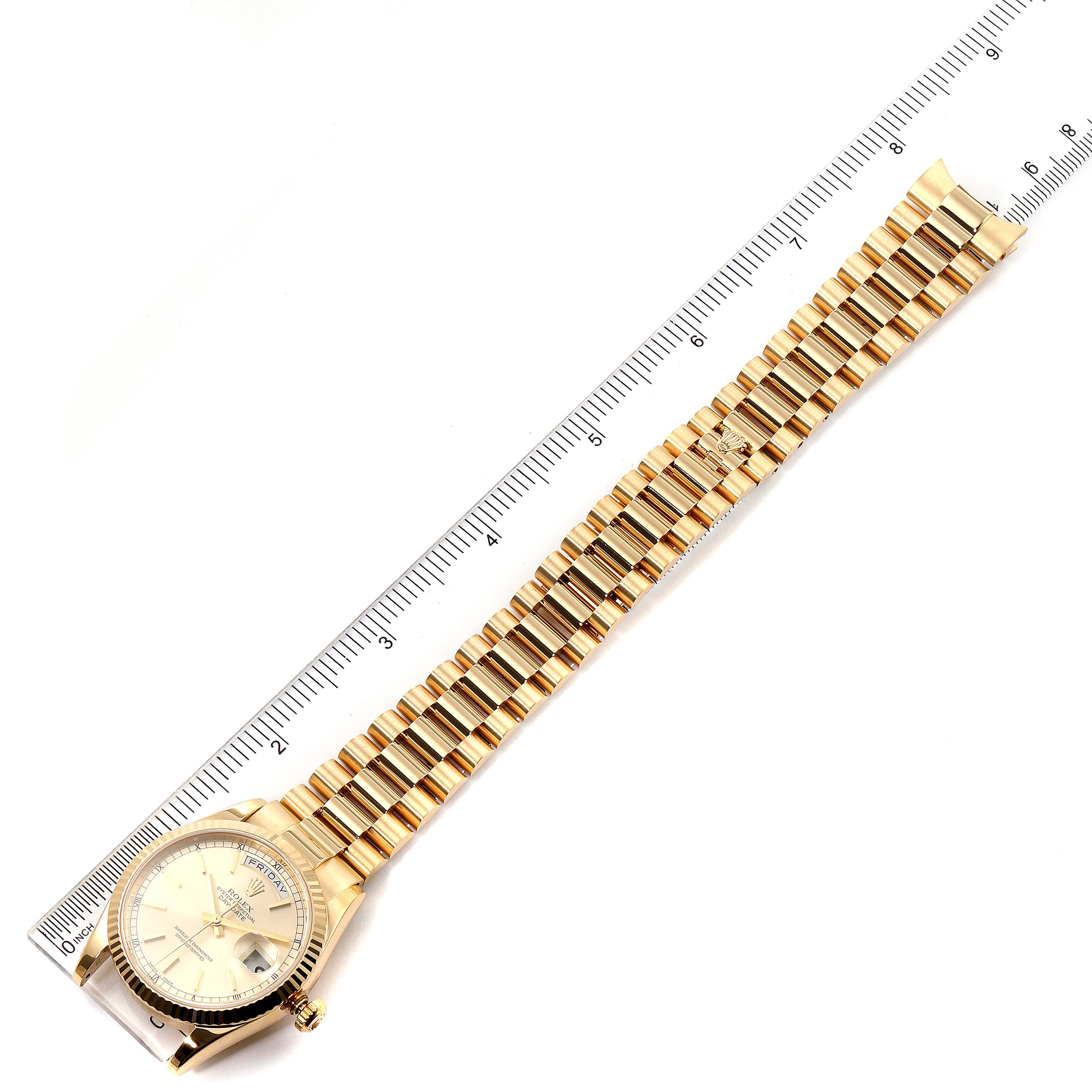 This is an overhead view of a Rolex President 118238 Men
s Yellow Gold Champagne Dial 118238 Men
s Yellow Gold Champagne Dial watch showing the face, bezel, crown, and full bracelet alongside a ruler.