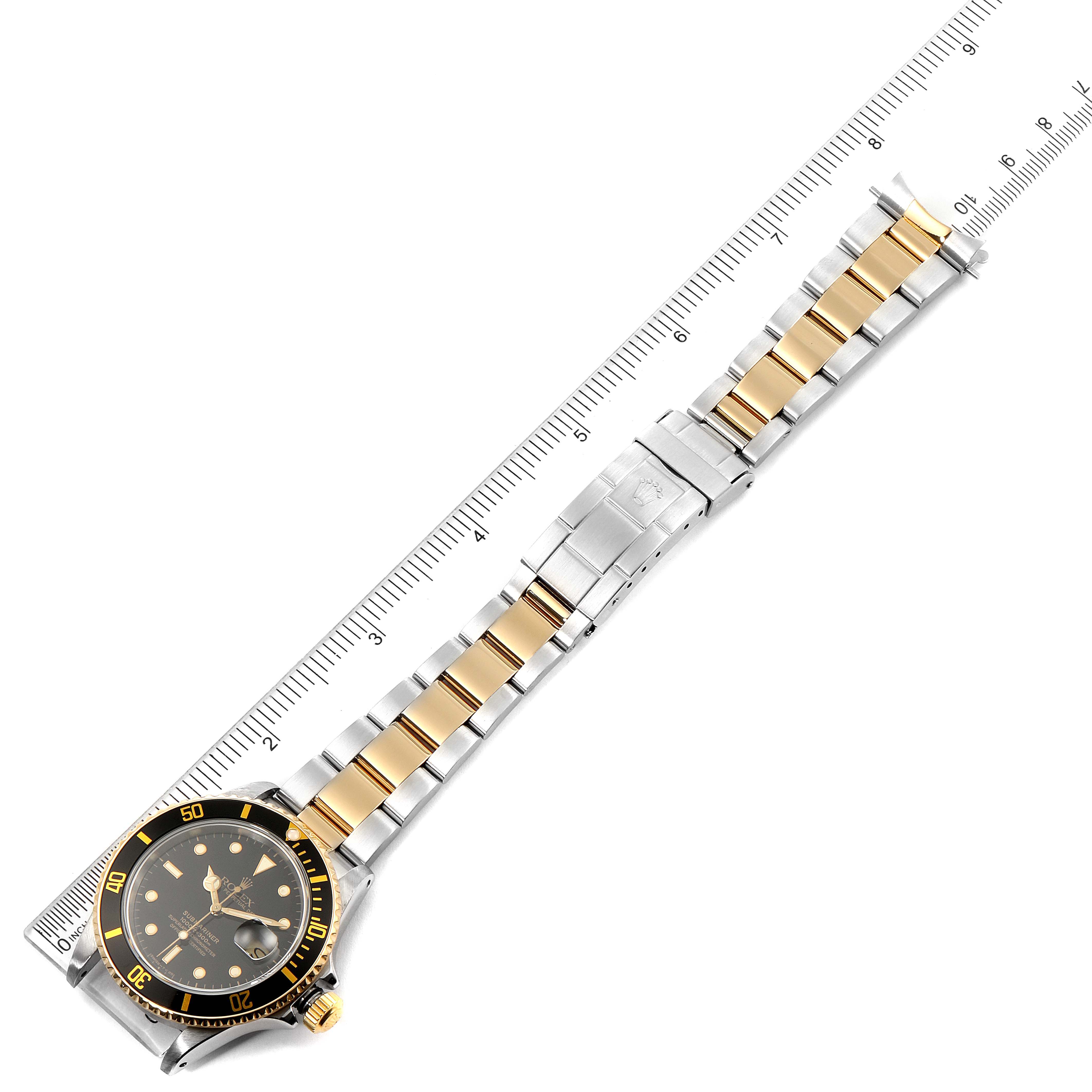 The image shows a Rolex Submariner 16803 Men's Steel and Gold (two tone) Black Dial 16803 Men's Steel and Gold (two tone) Black Dial watch laid flat with a ruler, highlighting the bracelet and face.