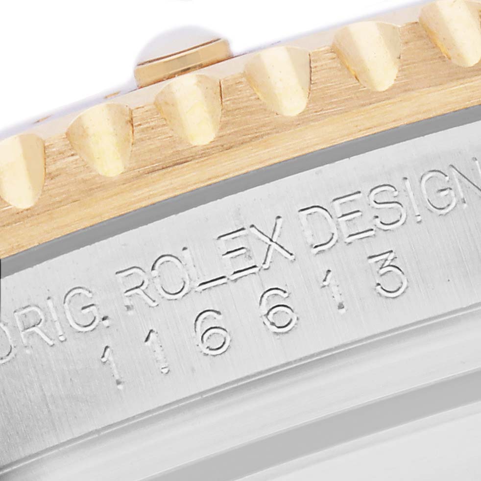 The image shows a close-up of the bezel and case edge of a Rolex Submariner 116613 Men's Steel and Gold (two tone) Blue Dial, highlighting the engravings and part of the fluted bezel.