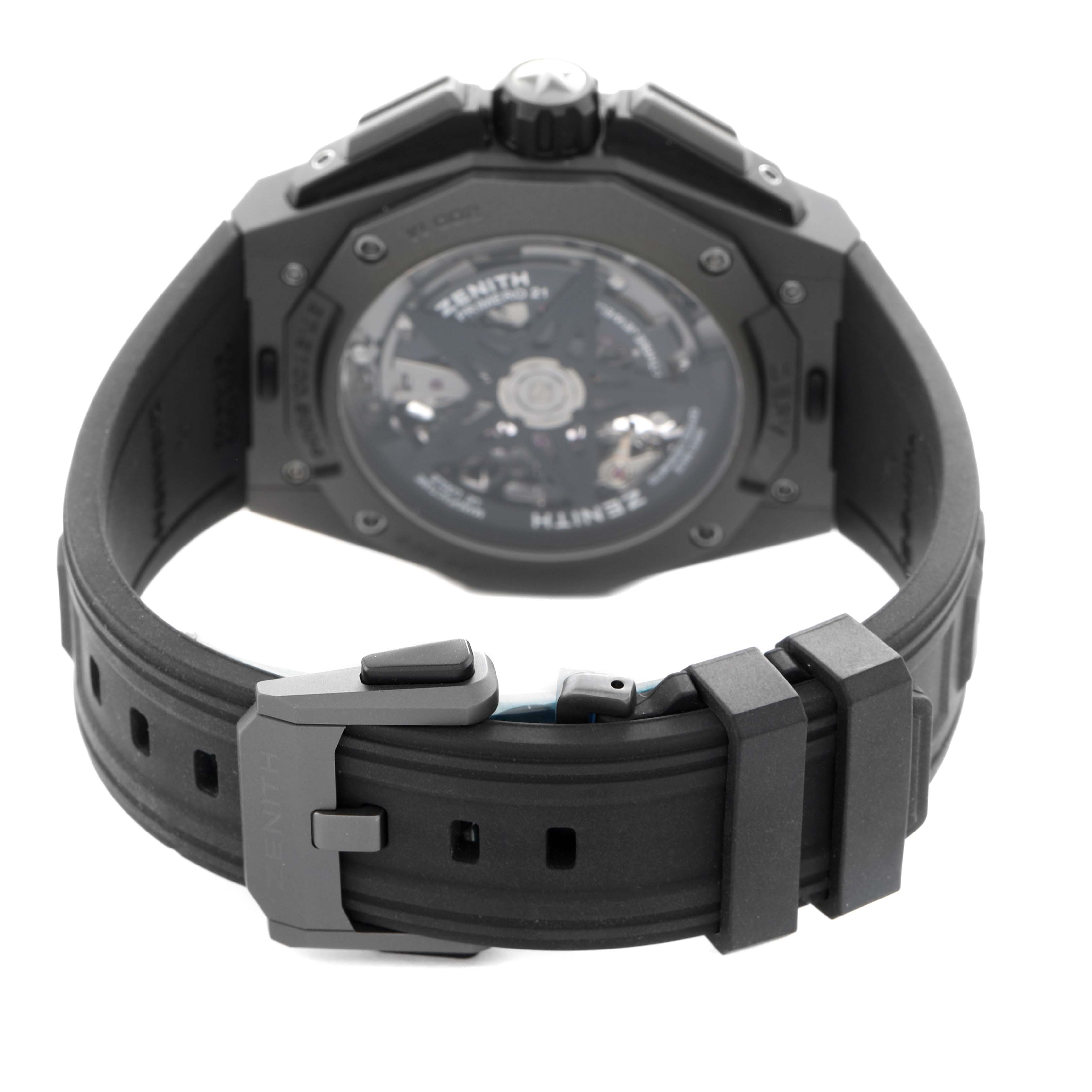 The image shows the back view of a Zenith Defy 97.9100.9004/02.I001 Men's Titanium Grey Dial watch, highlighting the strap, clasp, and transparent case back.