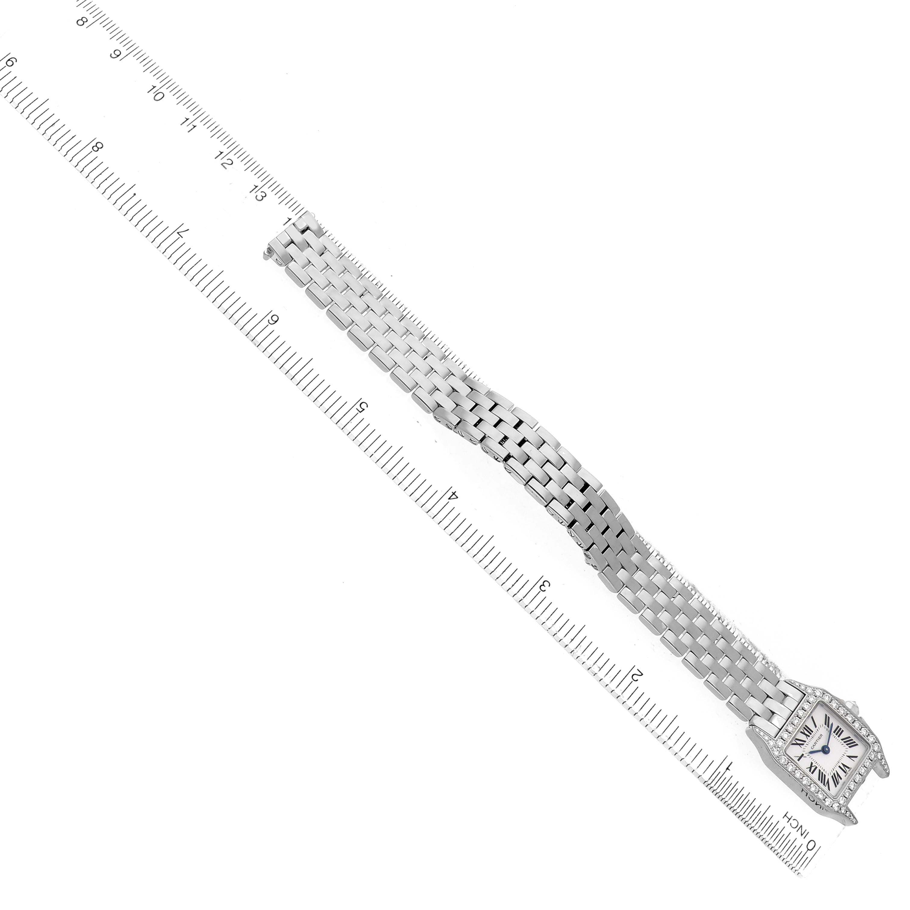 The Cartier Santos Demoiselle WF9005Y8 Women's White Gold Silver Dial watch is shown flat from above, displaying its face and full linked bracelet alongside a ruler for scale.