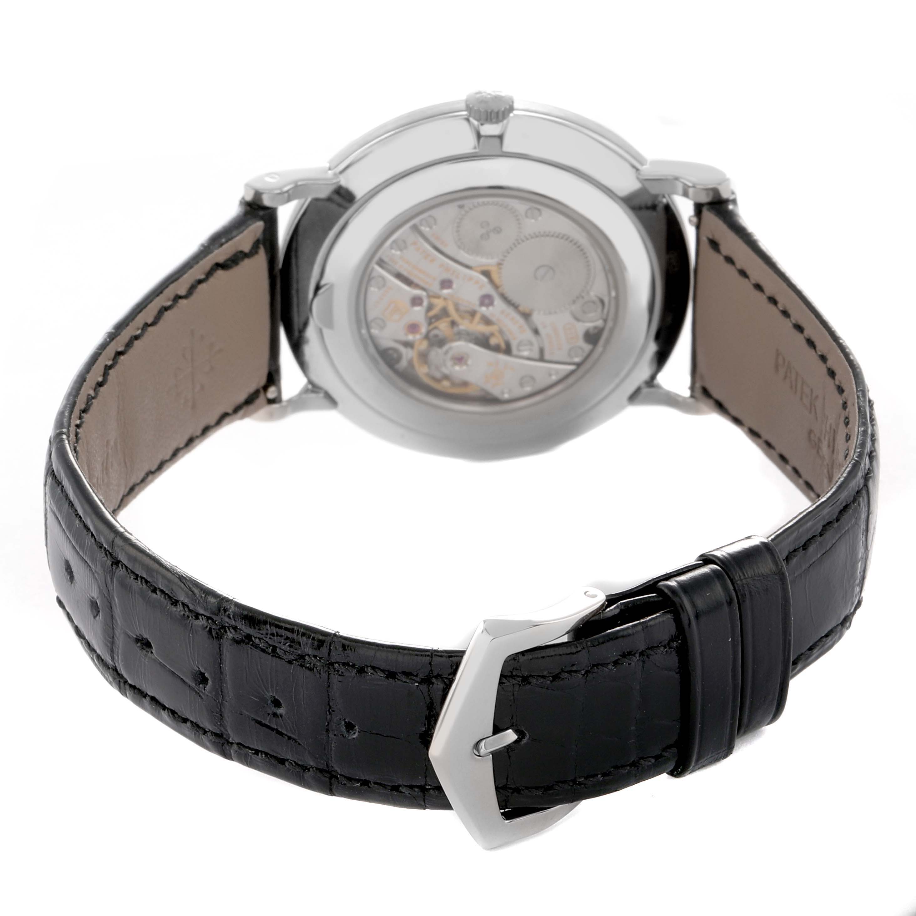 The image shows the back of a Patek Philippe Calatrava 5119G-001 Men's White Gold White Dial watch, featuring a view of the movement and a black leather strap with a buckle.