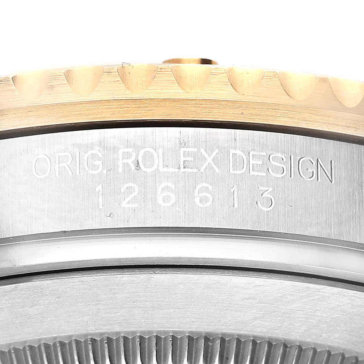 The image shows a close-up of the side of the Rolex Submariner 126613LN Men
s Steel and Gold (two tone) Black Dial 126613LN Men
s Steel and Gold (two tone) Black Dial, highlighting the model number engraving and bezel edge.