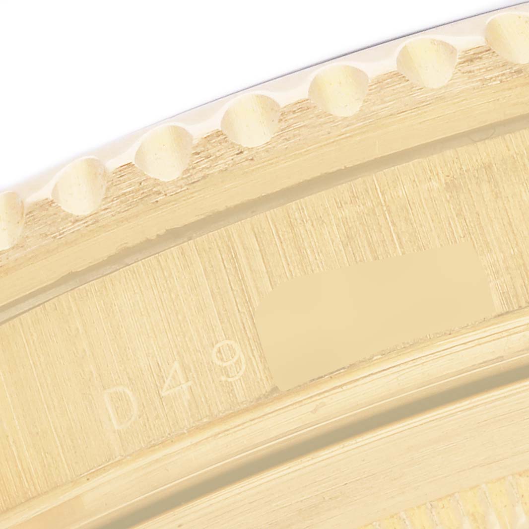 The image shows a close-up of the side of the bezel and part of the casing, highlighting the details and markings on a Rolex Submariner 16618 Men's Yellow Gold Blue Dial.
