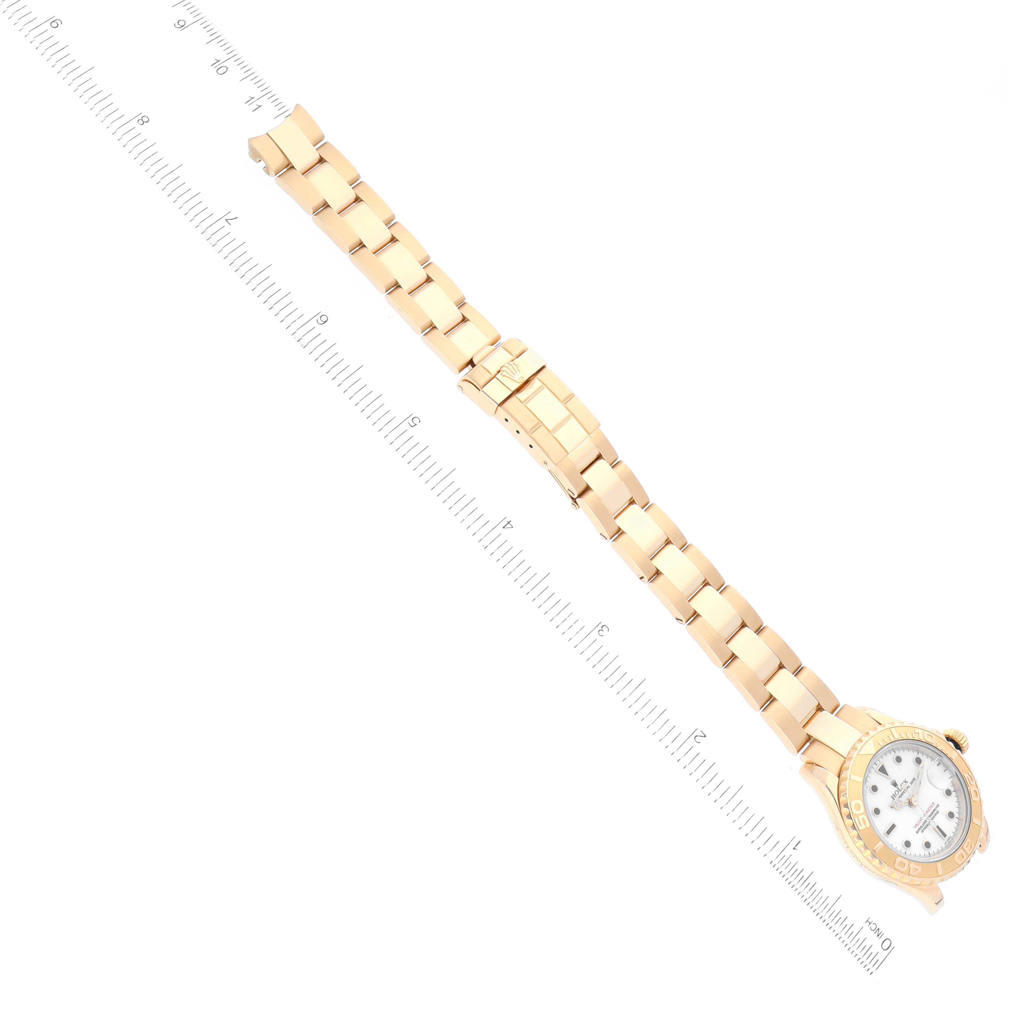 The image shows the Rolex Yacht-Master 69628 Women's Yellow Gold White Dial 69628 Women's Yellow Gold White Dial watch positioned flat with its gold bracelet extended and a ruler for scale.