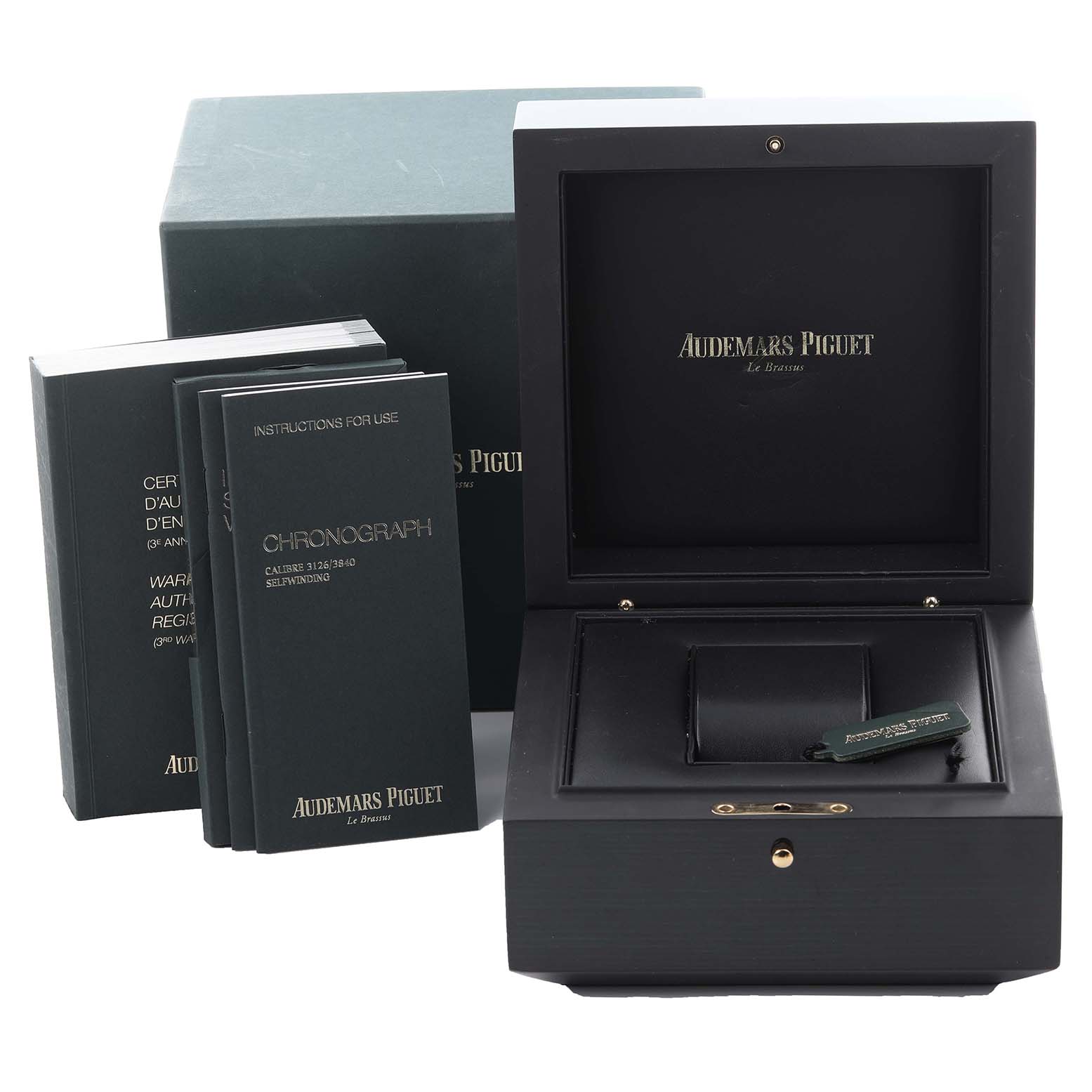 The image shows a Royal Oak Offshore box by Audemars Piguet, along with manuals and a green tag.