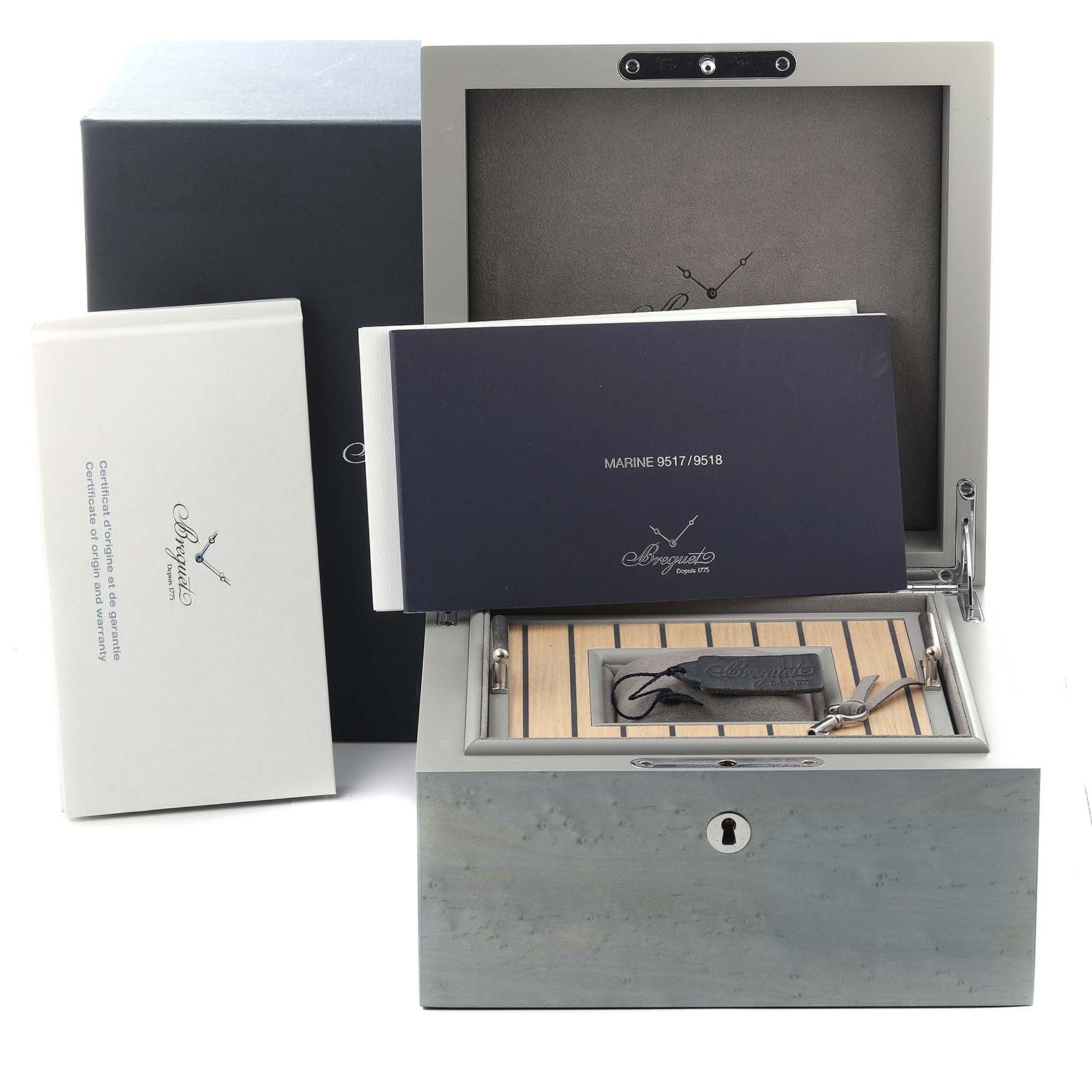 The image shows the Breguet 9517ST/E2/984 Women's Stainless Steel Blue Dial 9517ST/E2/984 Women's Stainless Steel Blue Dial Marine watch box, an open wooden case, and accompanying documentation.