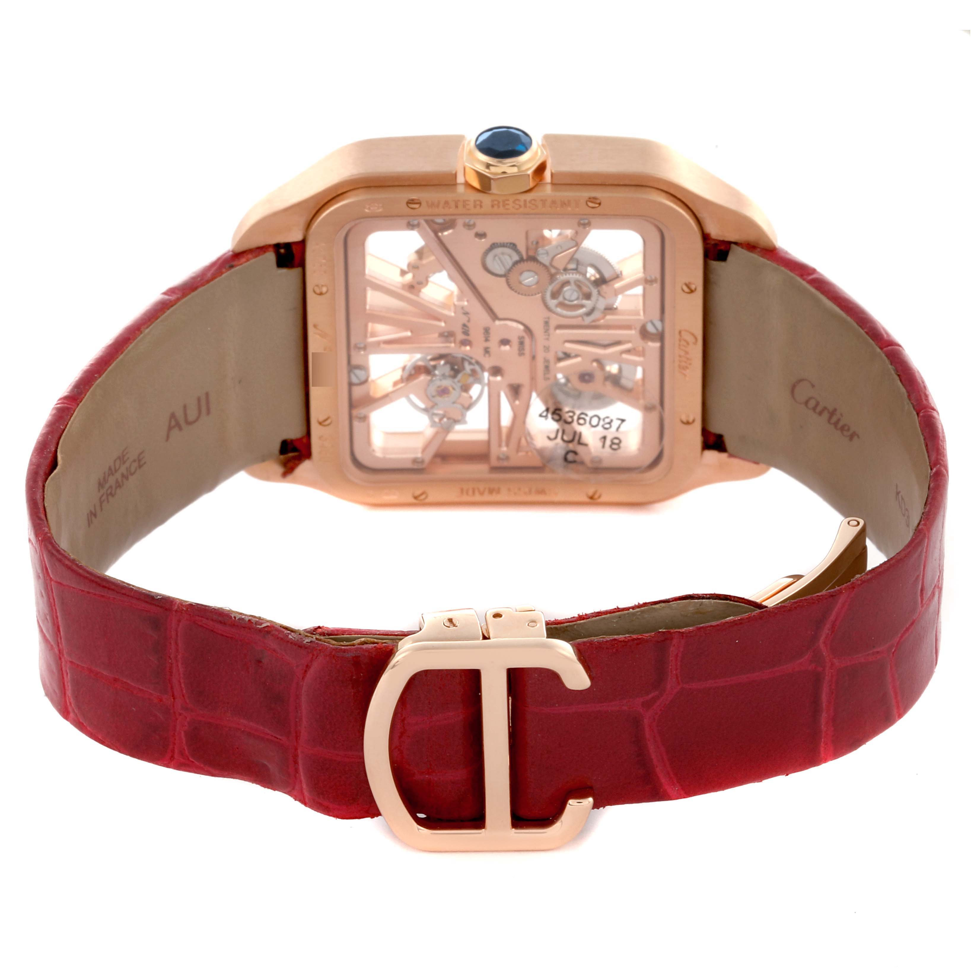 The Cartier Santos W2020057 Men's Rose Gold Transparent Dial W2020057 Men's Rose Gold Transparent Dial watch is shown from the back, highlighting the open case back and red leather strap with buckle.