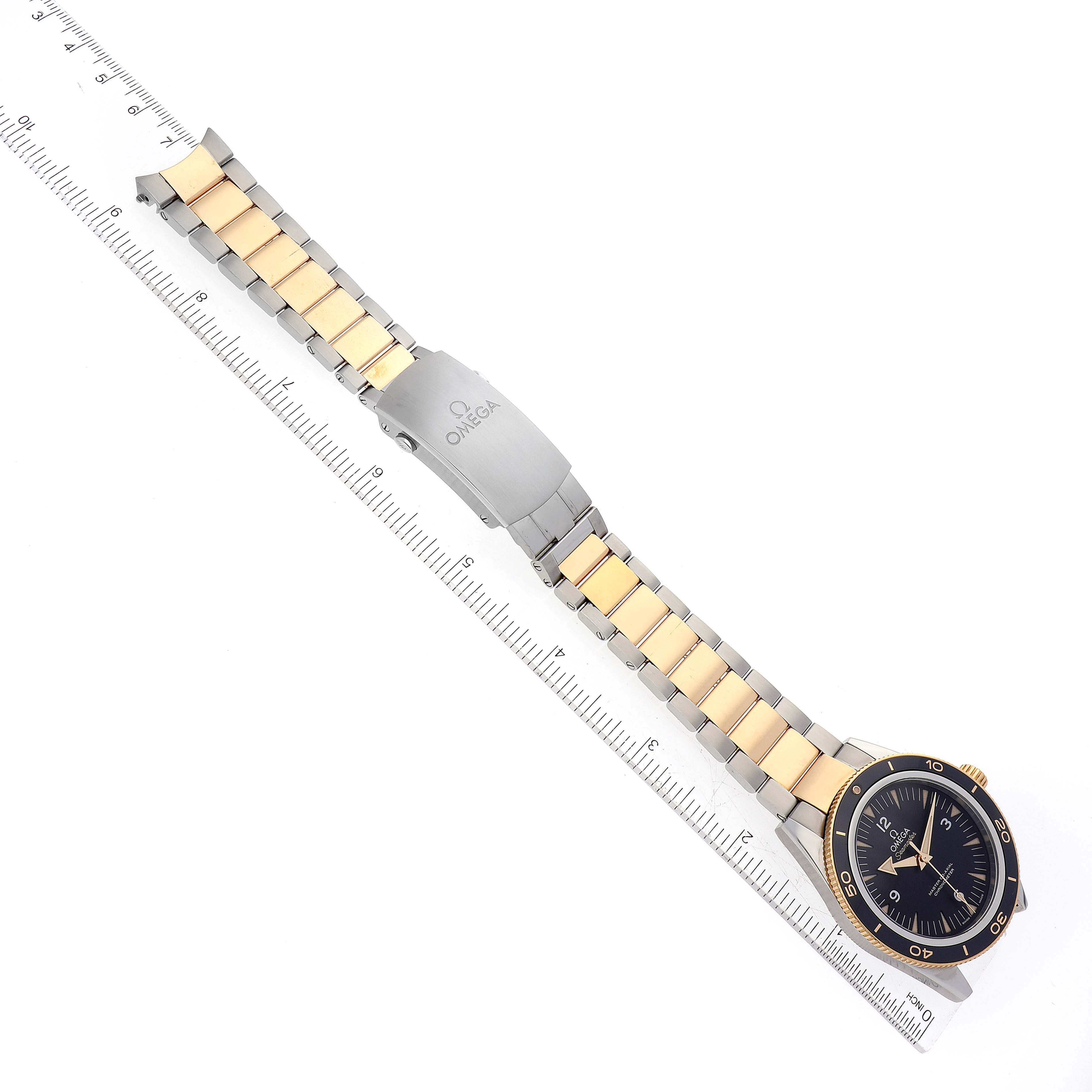 The image shows an Omega Seamaster 233.20.41.21.01.002 Men's Steel and Gold (two tone) Black Dial 233.20.41.21.01.002 Men's Steel and Gold (two tone) Black Dial watch laid flat with its face, bezel, bracelet, and clasp visible, alongside a ruler for scale.