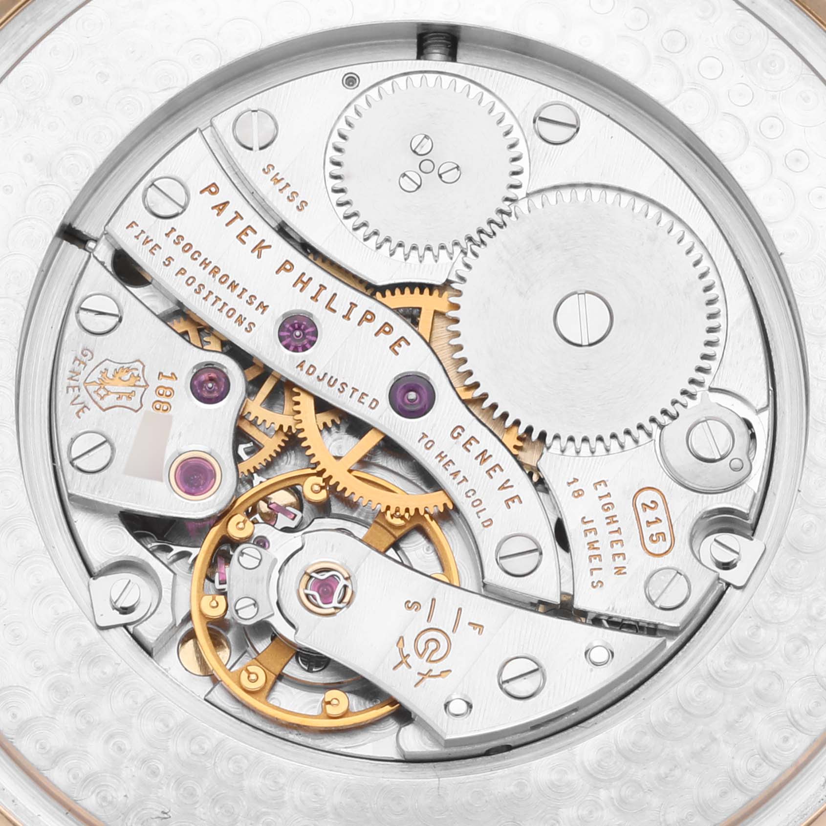 The image shows a close-up of the Calatrava's intricate movement and gears from Patek Philippe.