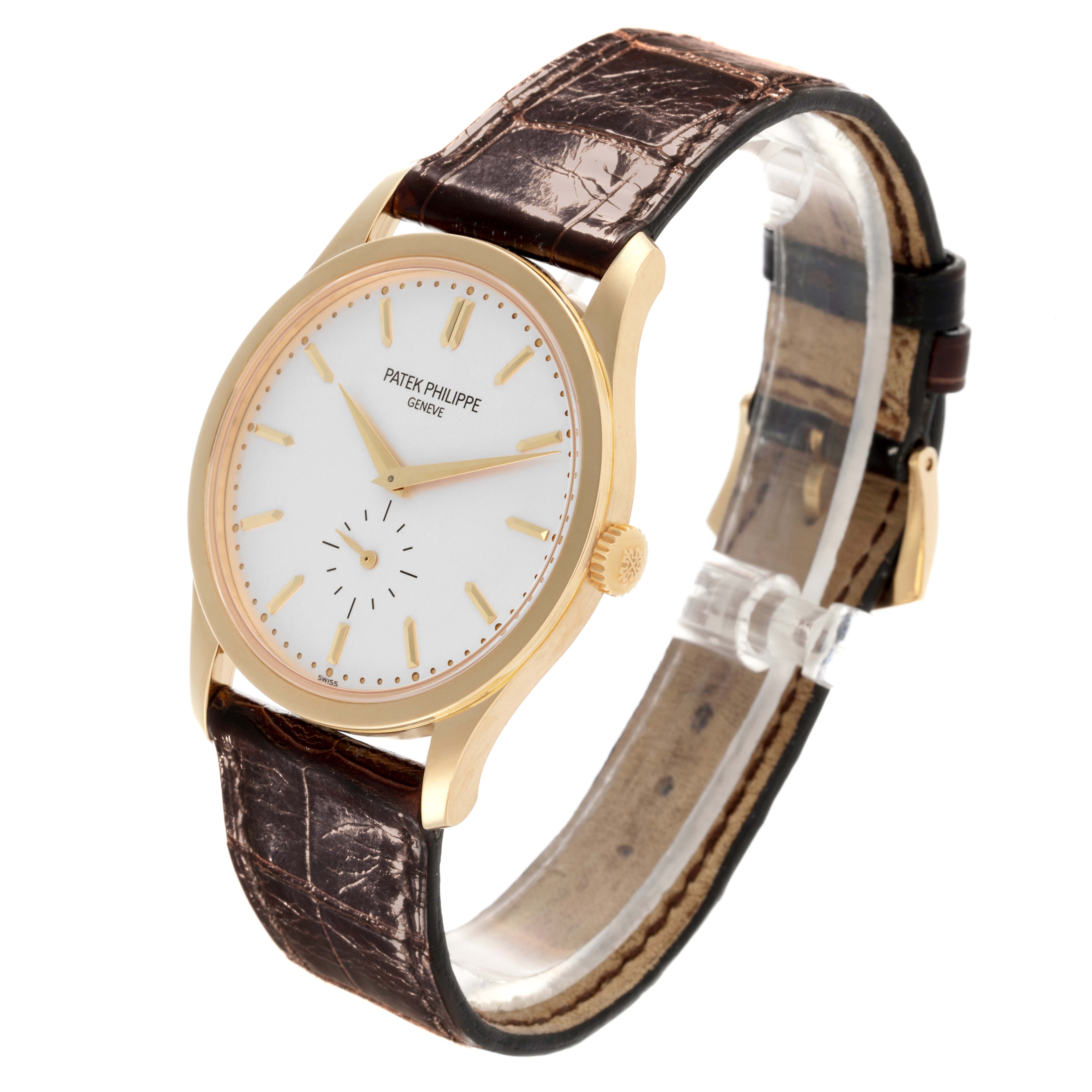 The Patek Philippe Calatrava 5196J-001 Men's Yellow Gold Silver Dial 5196J-001 Men's Yellow Gold Silver Dial watch is shown at an angled view, highlighting the case, dial, crown, and brown leather strap.
