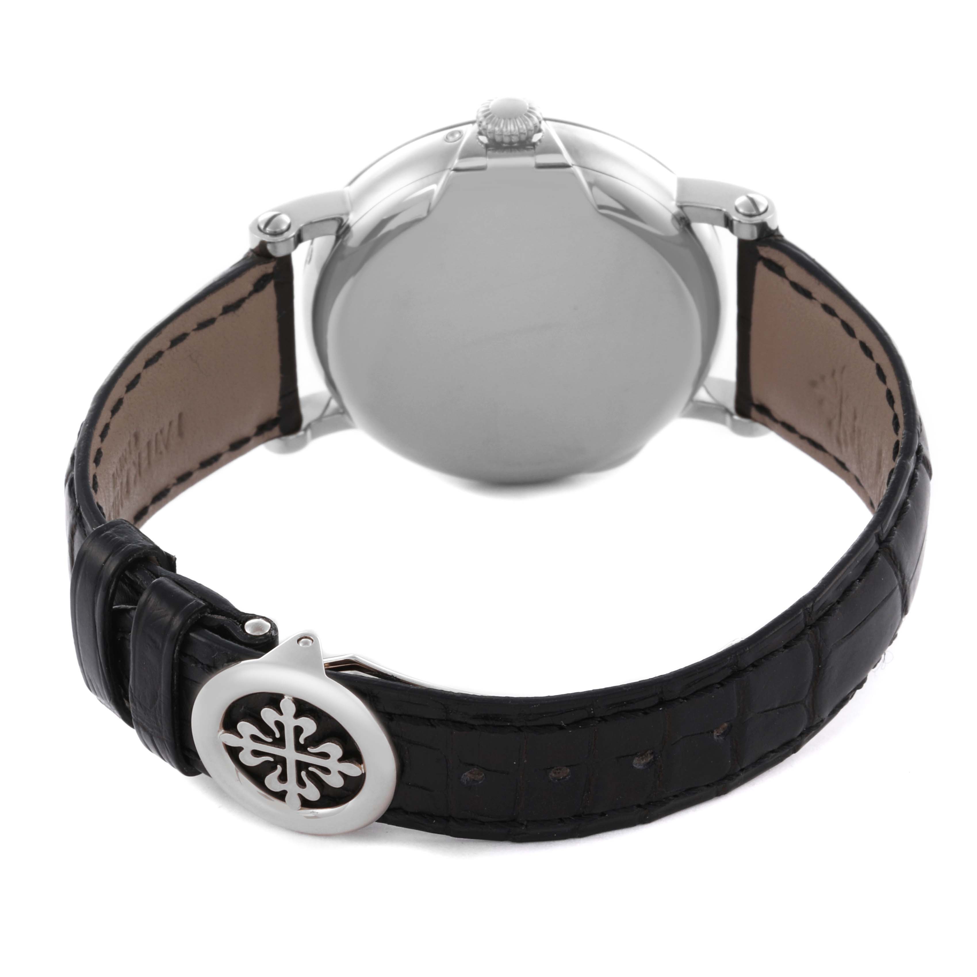 The Patek Philippe Complications 5159G-001 Men's White Gold White Dial 5159G-001 Men's White Gold White Dial watch is shown from the back, highlighting the case, crown, and leather strap with a logo clasp.