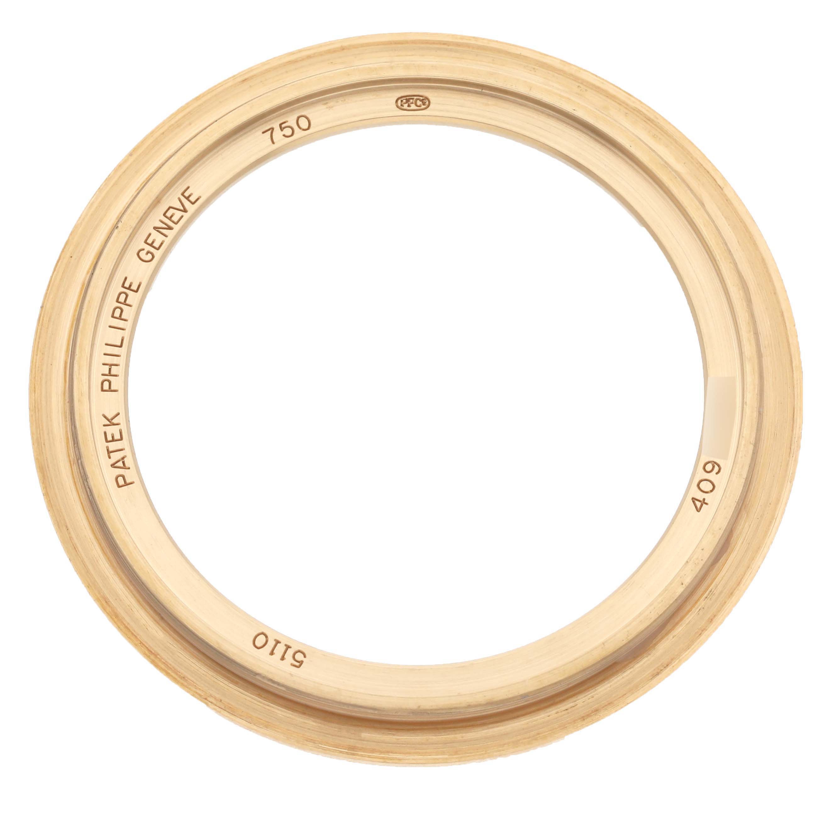 The image shows a Patek Philippe Complications 5110J-001 Men's Yellow Gold Silver Dial 5110J-001 Men's Yellow Gold Silver Dial watch bezel, viewed from above, featuring engravings.